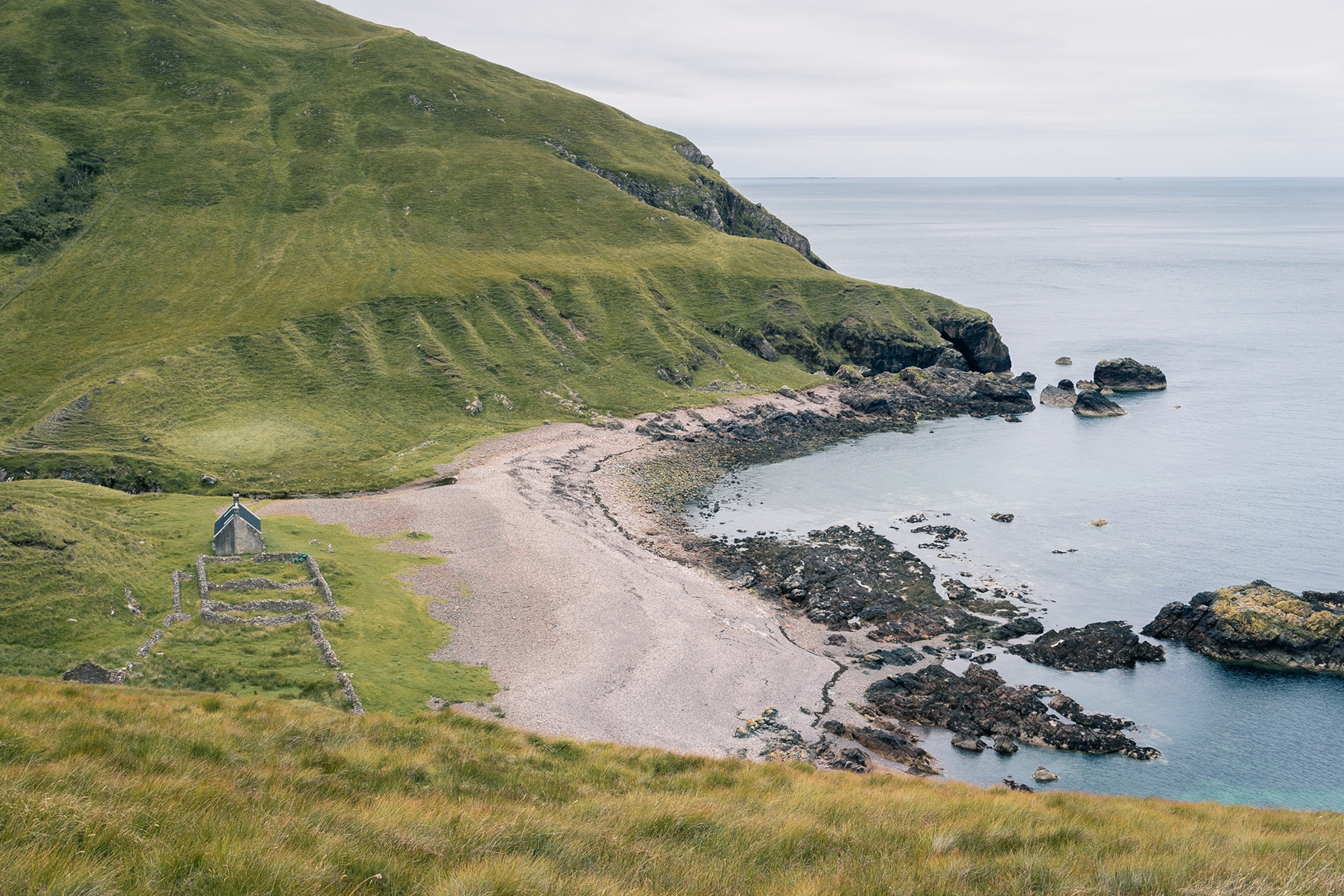 A view onto a windy and rocky Scottish bay surrounded by hills.