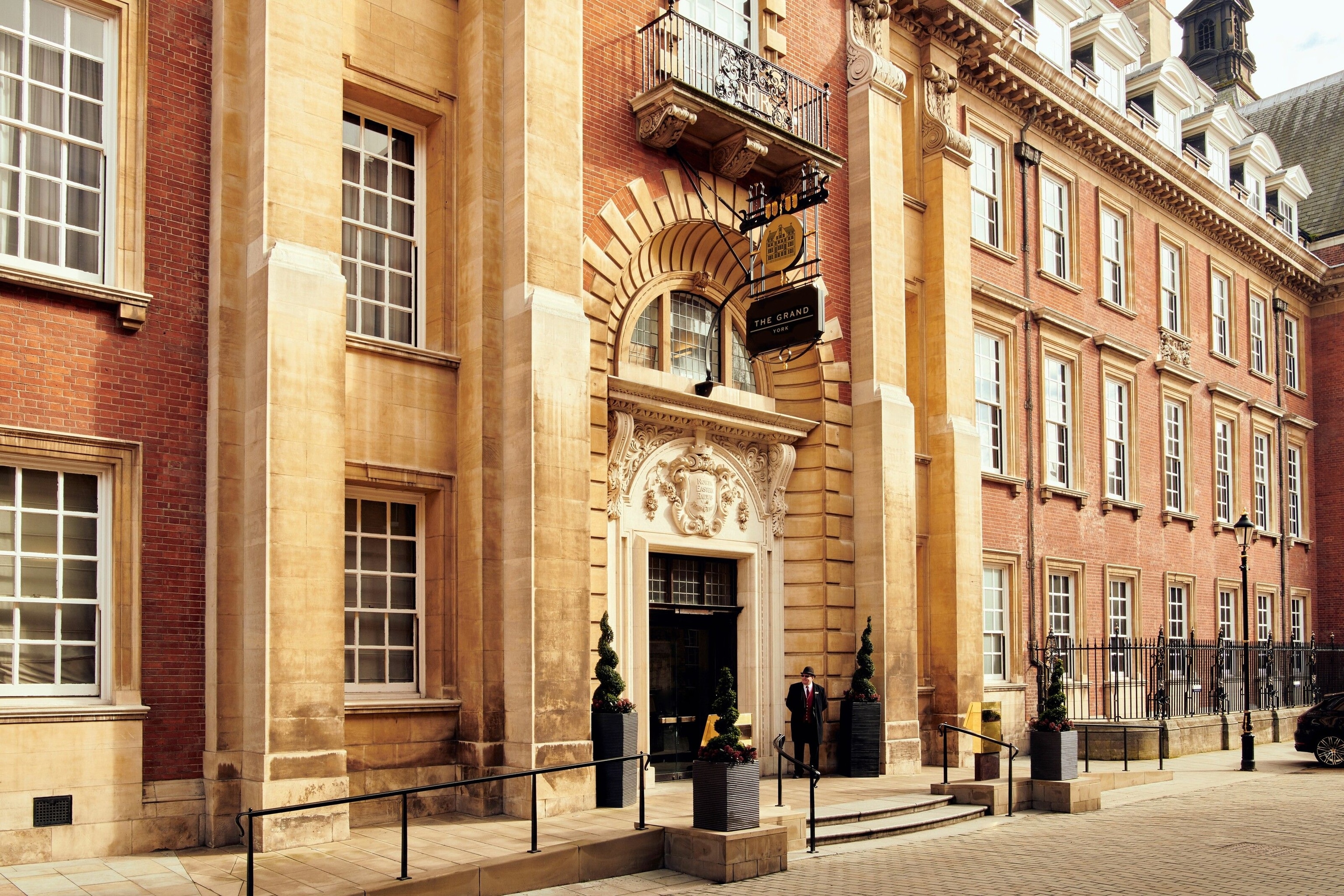 The Grand, York, pictured from the outside. It is a large building. The doorway is particularly noteworthy. It is a fresh black panel in a white arch, which has several layers of stone.