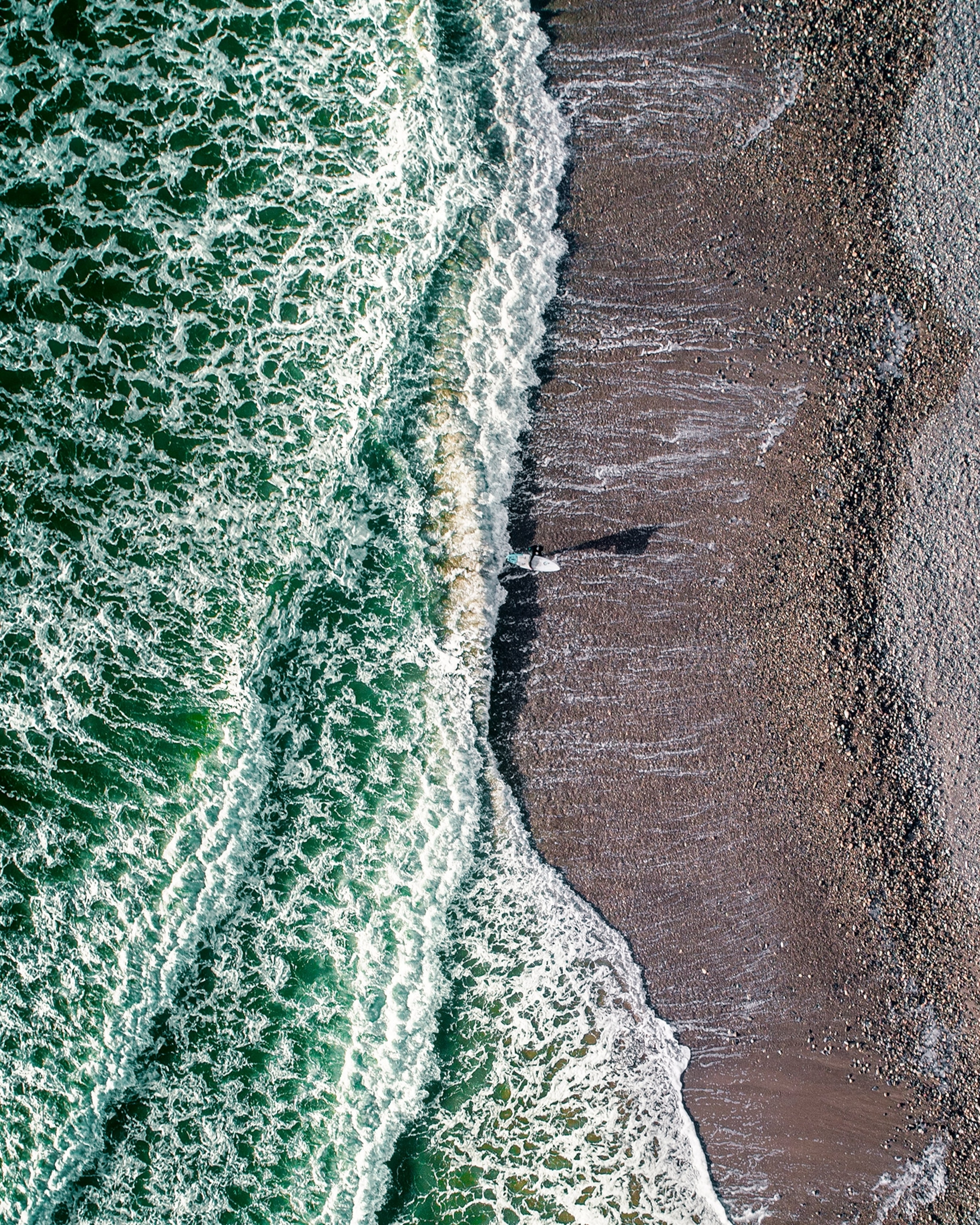 a surfer walking along a beach in Ireland