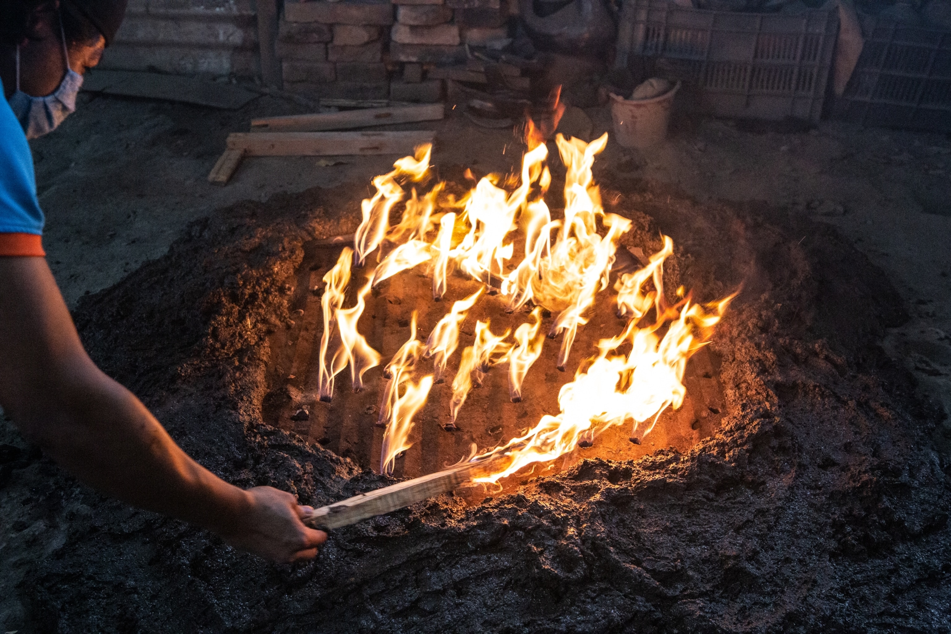 a women potter from the community of Coyotepec controls the kiln fire