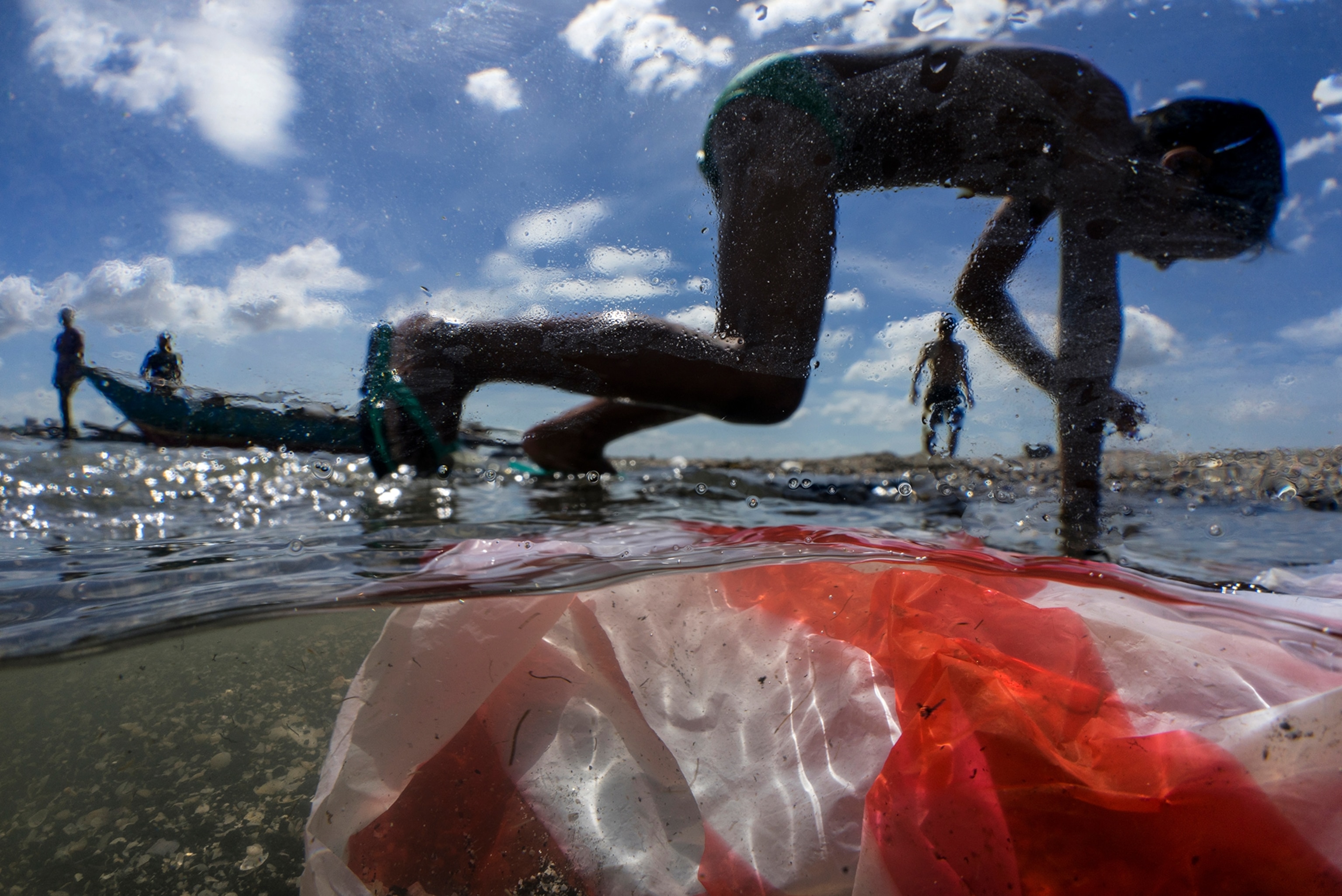 children playing in water polluted by household waste, plastics, and other trash