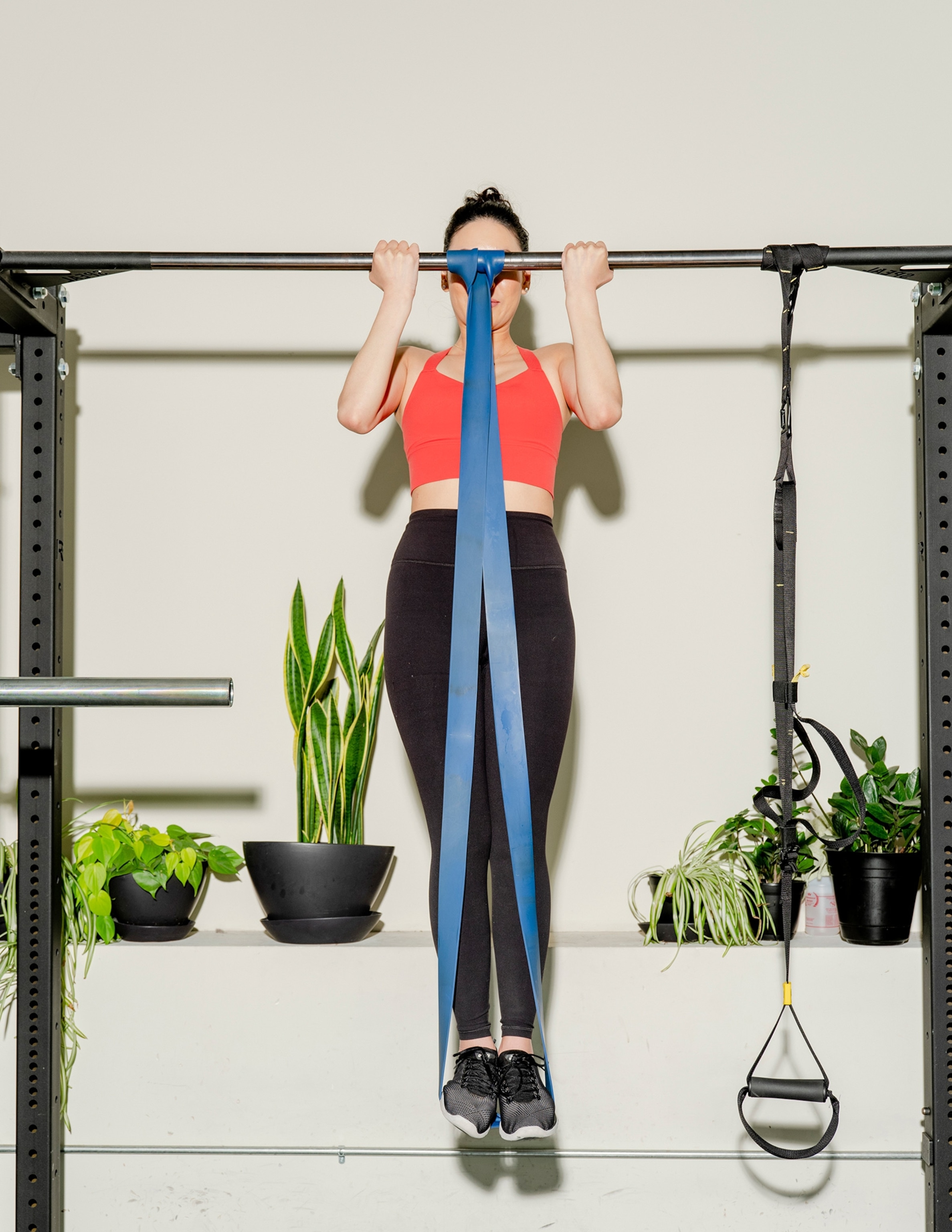 A woman does pullups with exercise bands.