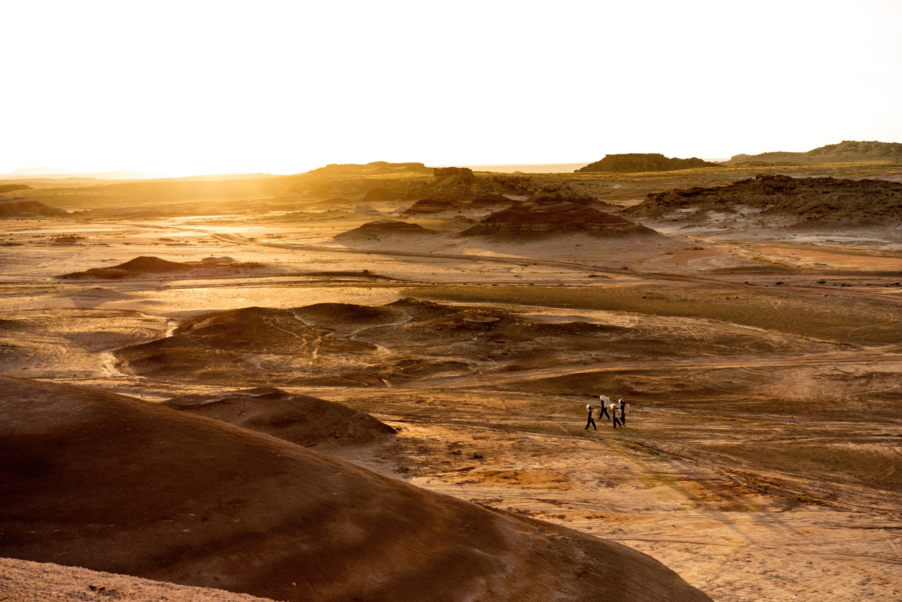 Piciture of members of the Mars Society, taking an evening walk outside their habitat in Utah.