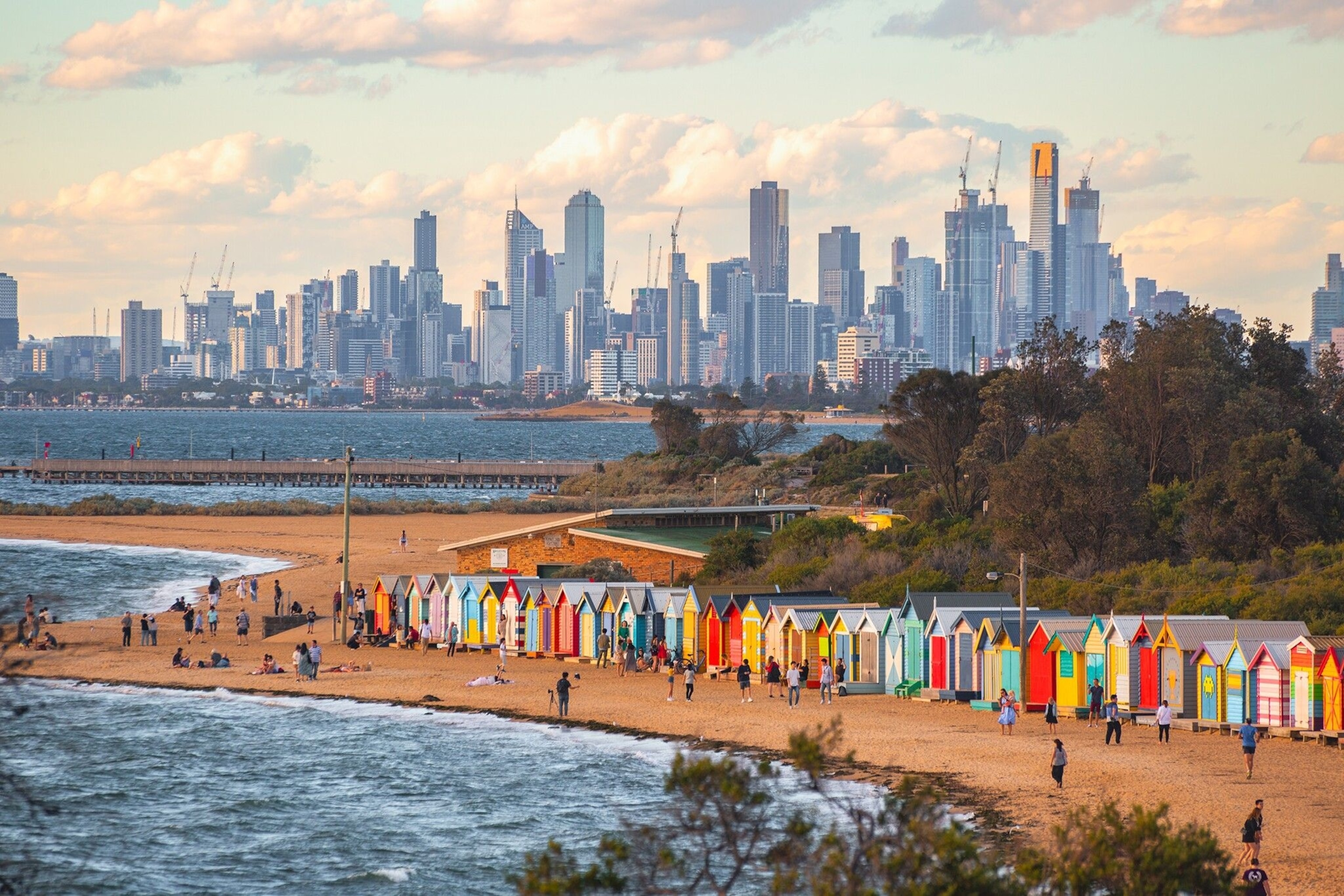 The Melbourne city skyline sits in the background of a beach on the outskirts of the city.