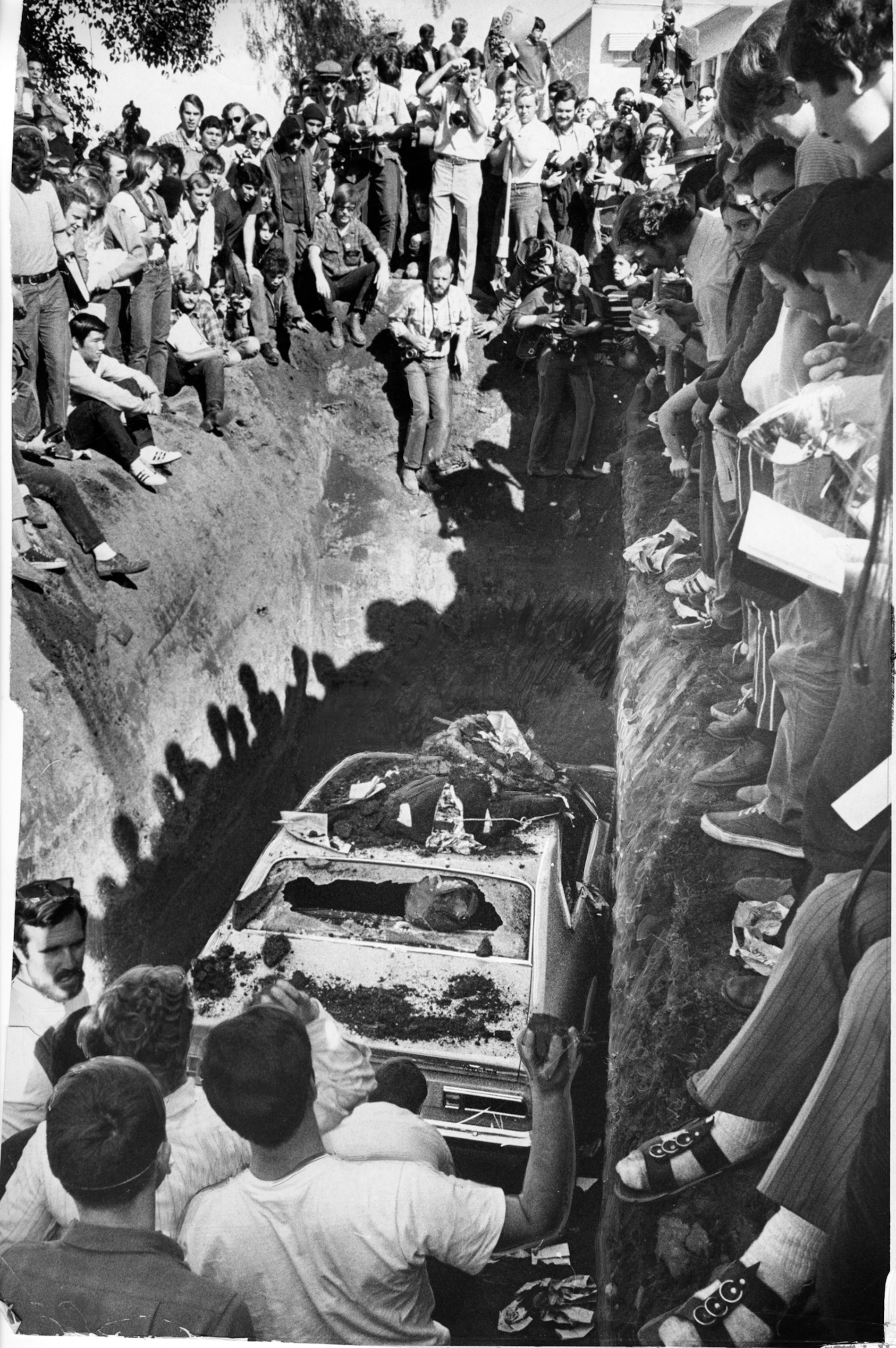 black and white picture of people burying a car