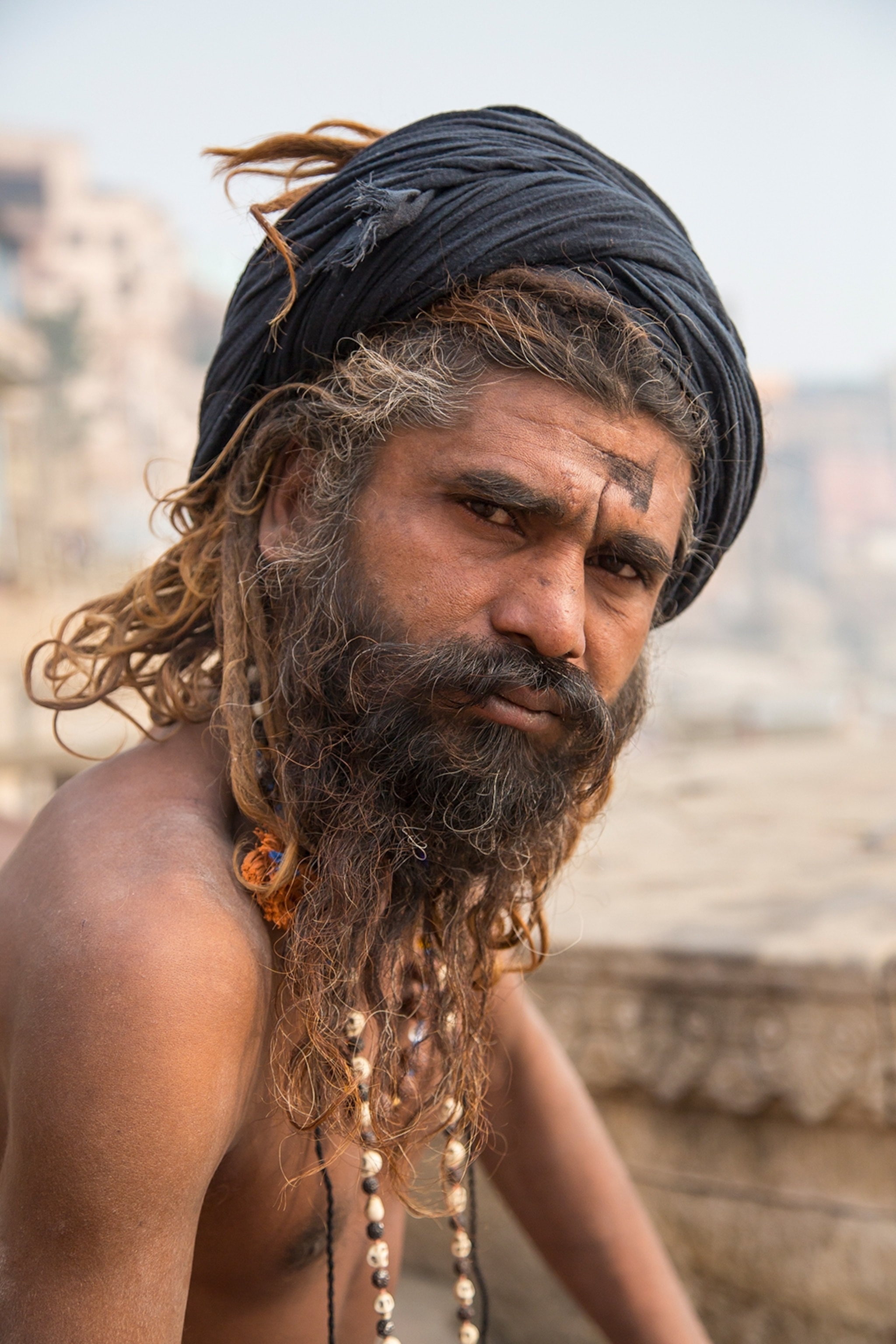 A man in Varanasi, India. He is wearing a black scarf to cover his unruly hair.
