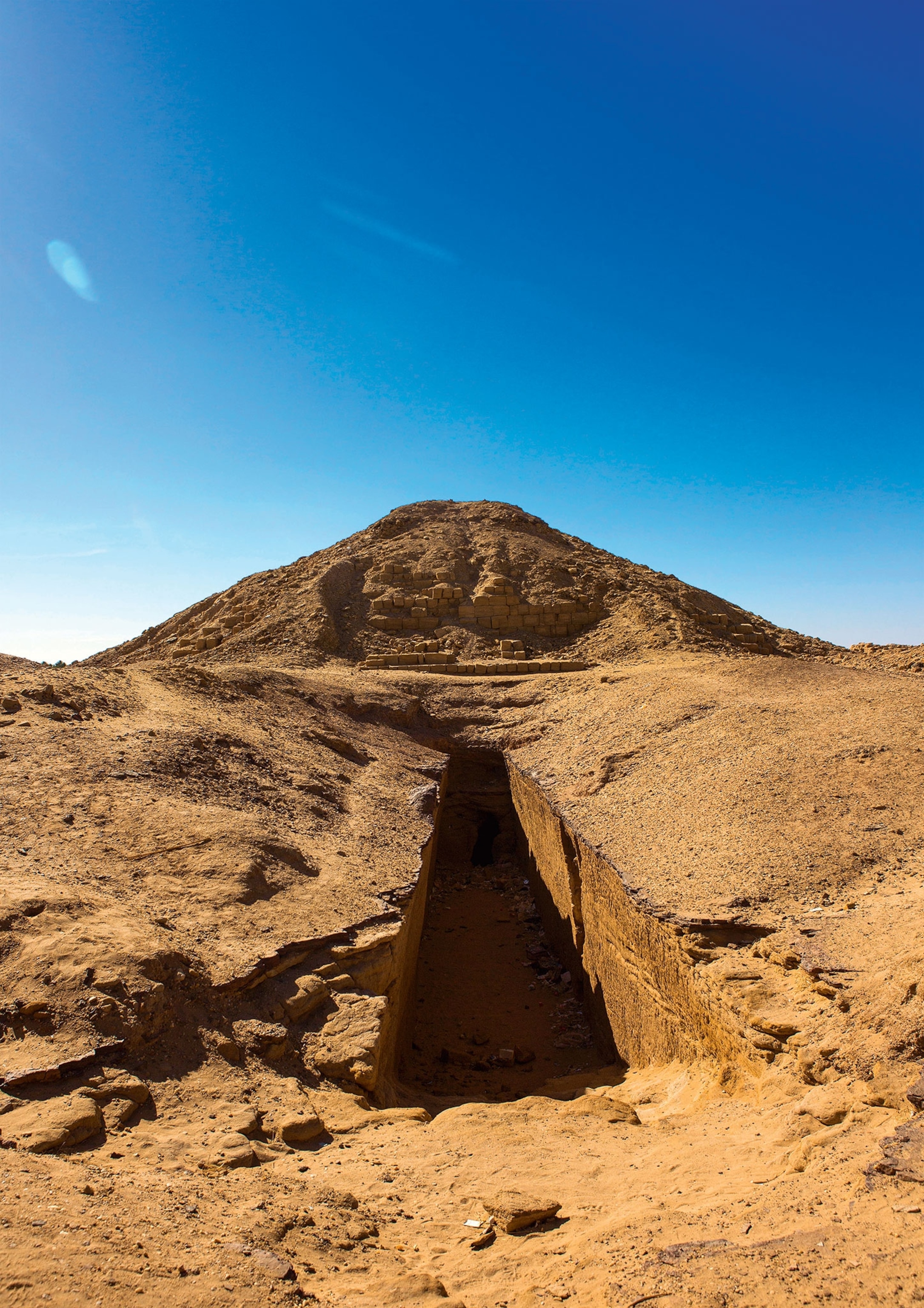 The ruins of large pyramid with a partially underground path leading to it in front