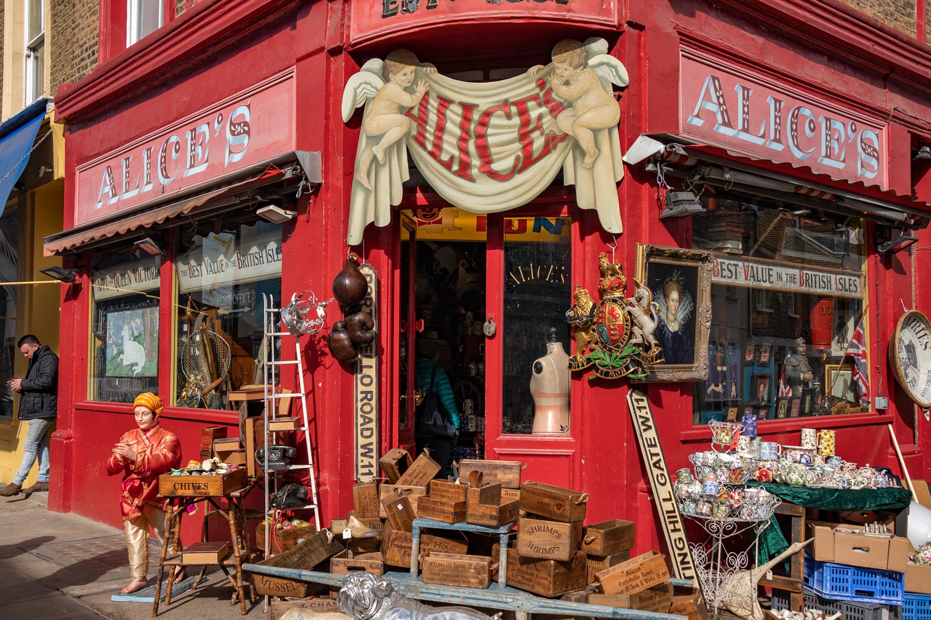 Exterior of a red corner store on a street with signs reading 'Alice's above the windows