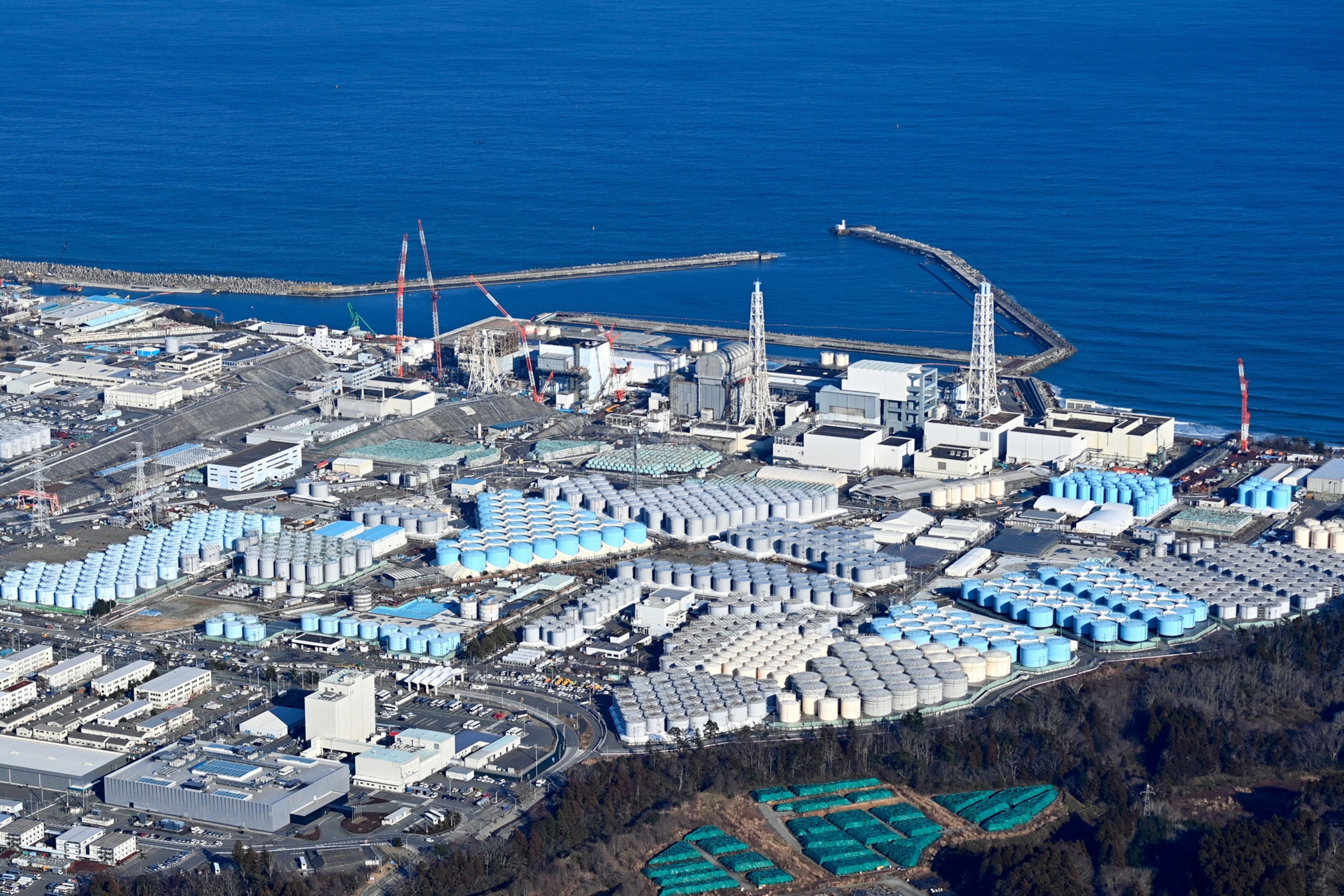 an aerial photo of damaged reactors and tanks next to a body of water