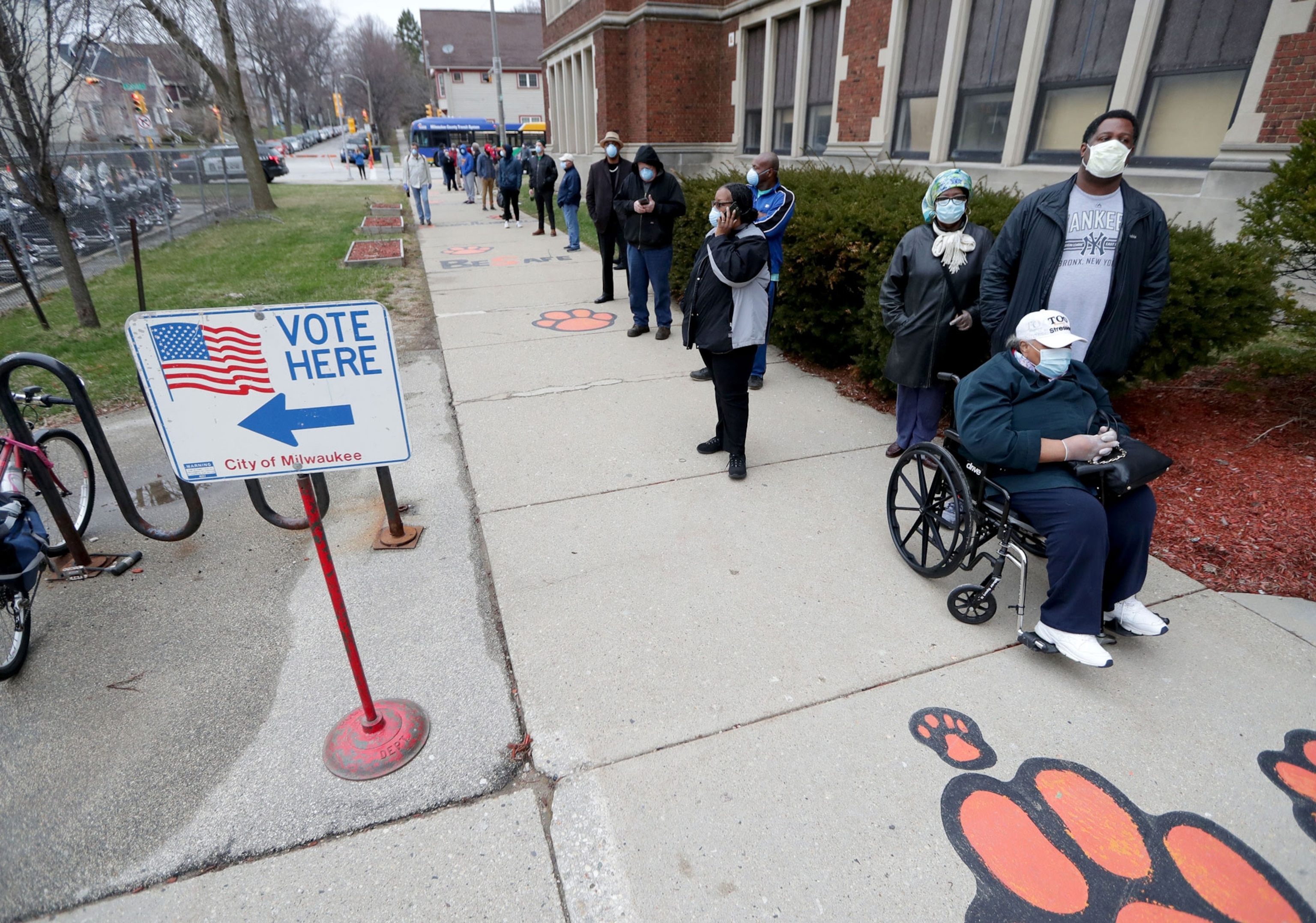 people waiting in line on a sidewalk to vote