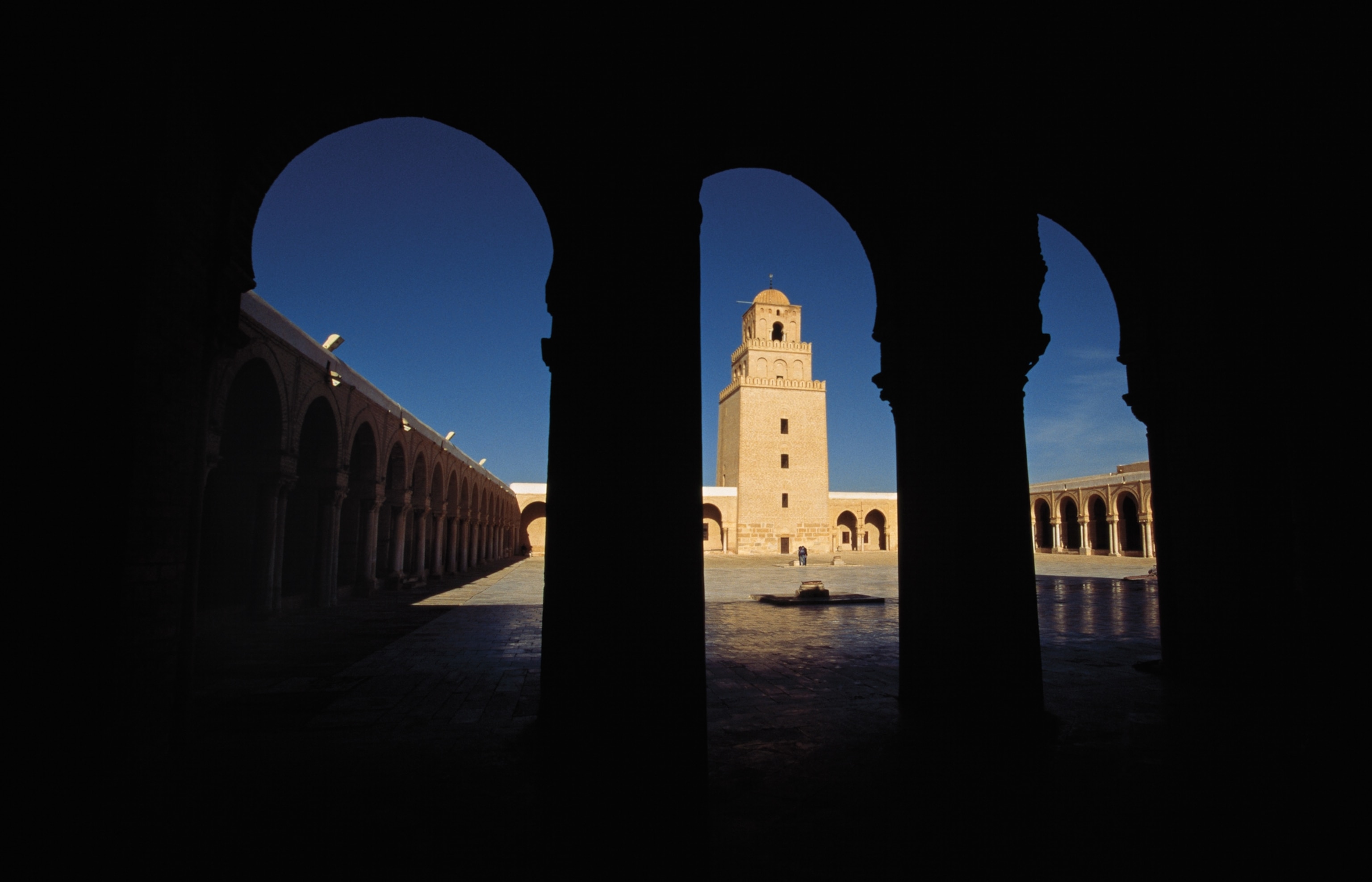 Photo of courtyard behind arch silhouettes