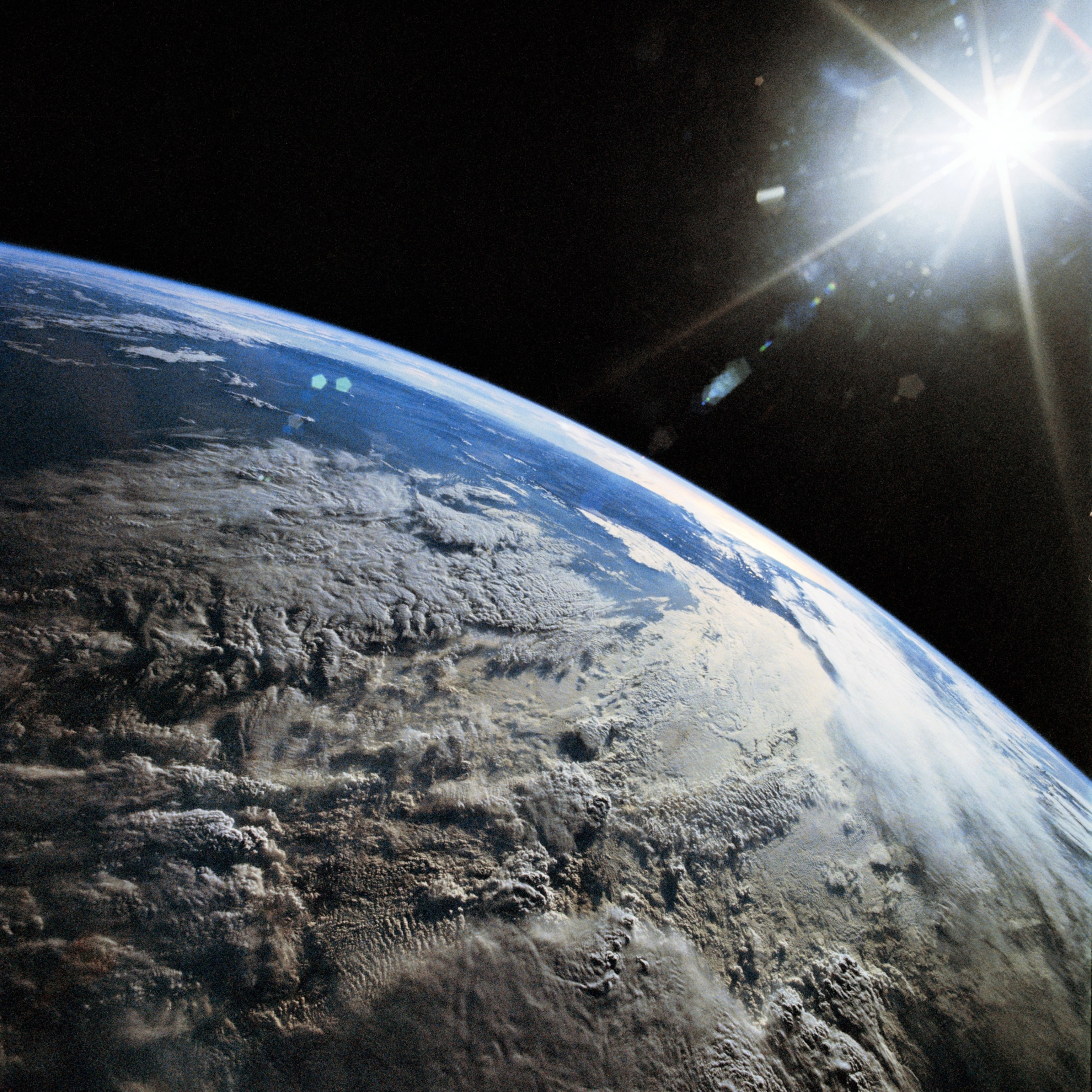 The Earth as seen from the Space Shuttle Discovery, with the sun in the upper right corner casting light across the Andes Mountains on Earth below.