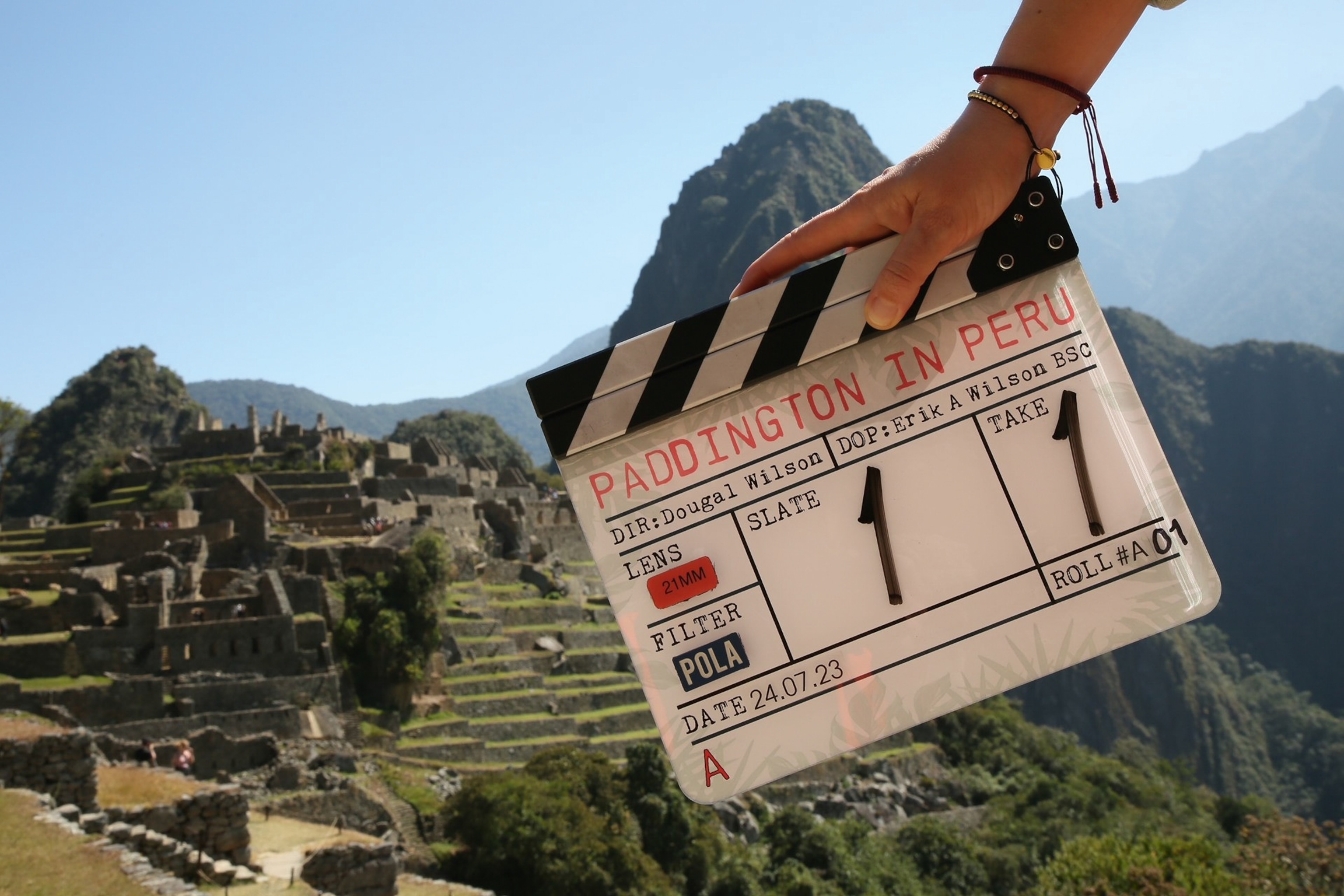 A director's clapperboard with 'Paddington in Peru' written on it in front of a historical landmark in Peru.
