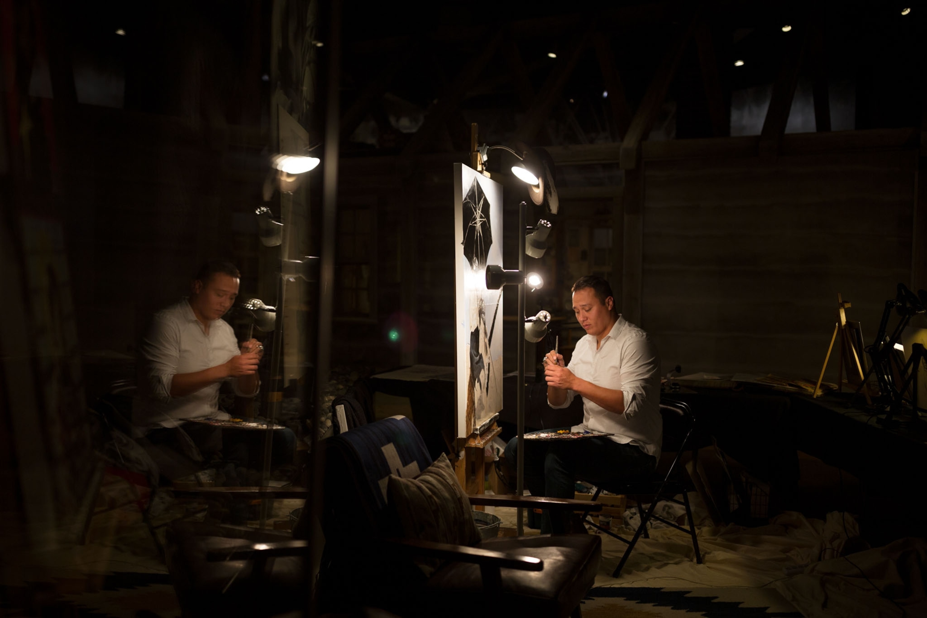 an artist painting in a studio that is dimly lit