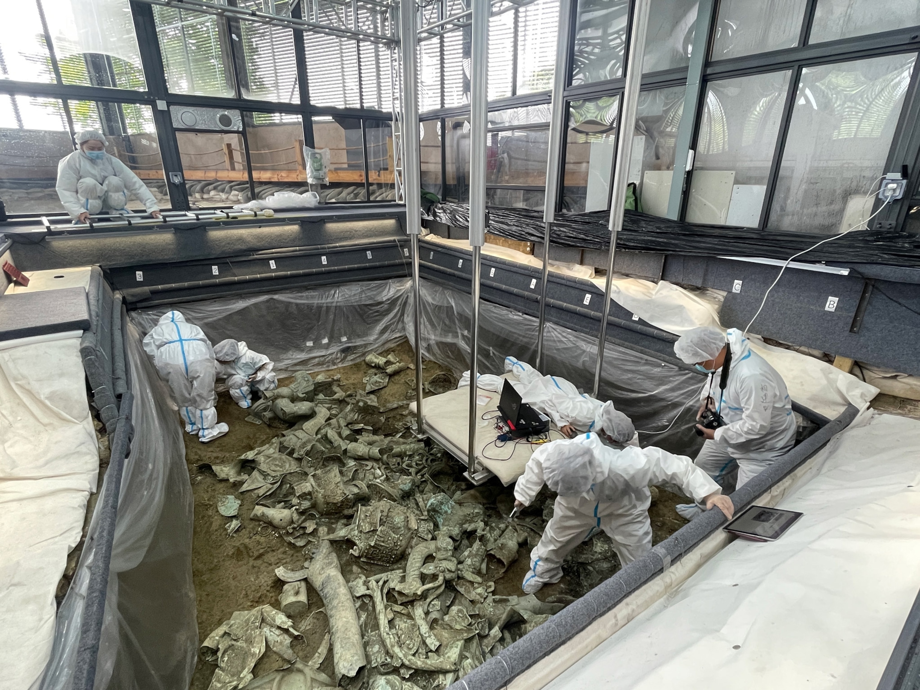 Photo of people in white suits in archeological pit