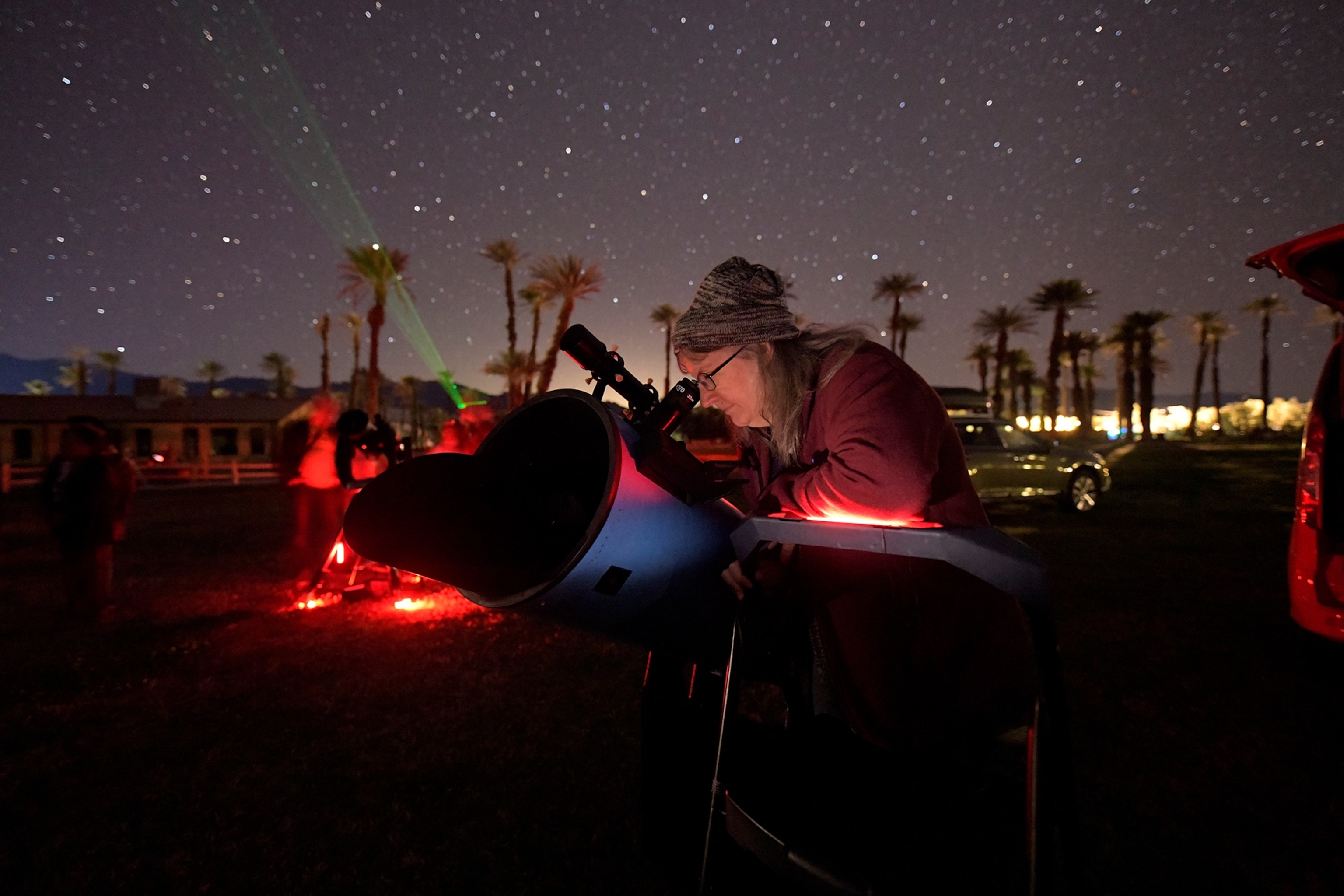 a woman looking into a telescope at night