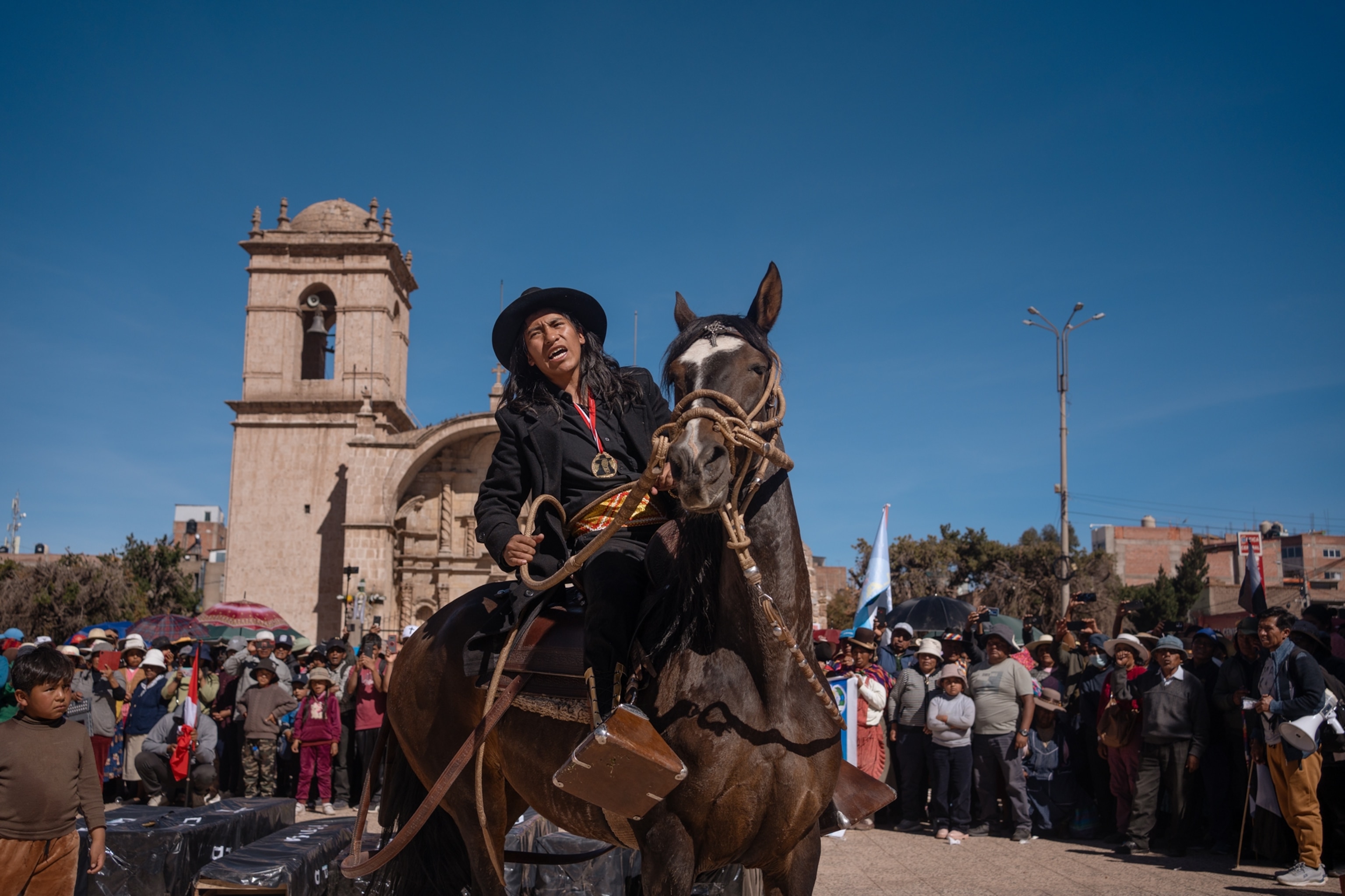 Man is seen on a horse in the middle of the mainsquare of Juliaca, singing as people gather around him.