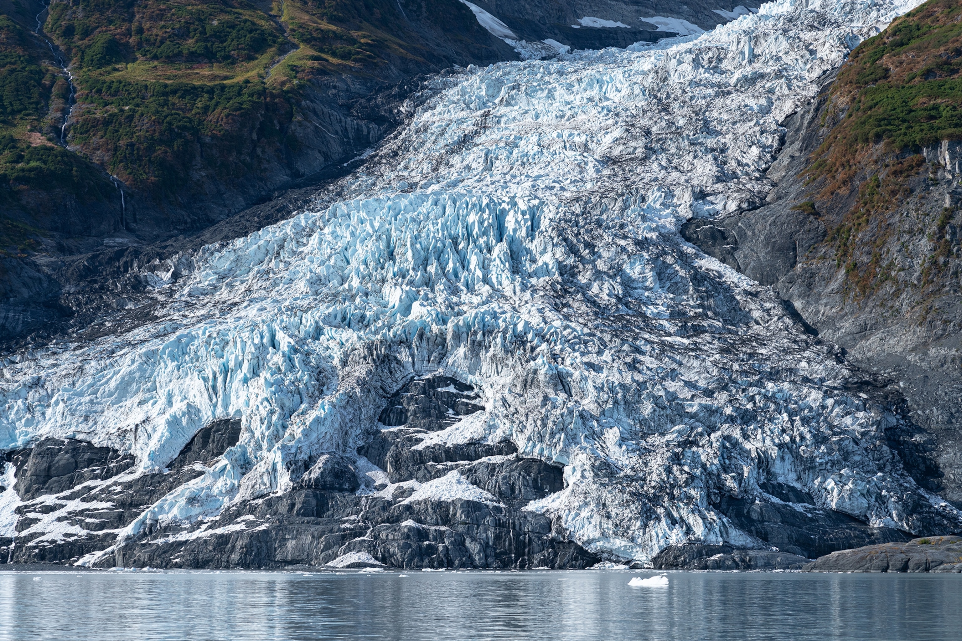 A rocky coastline with a frozen avalanche leading towards the water.