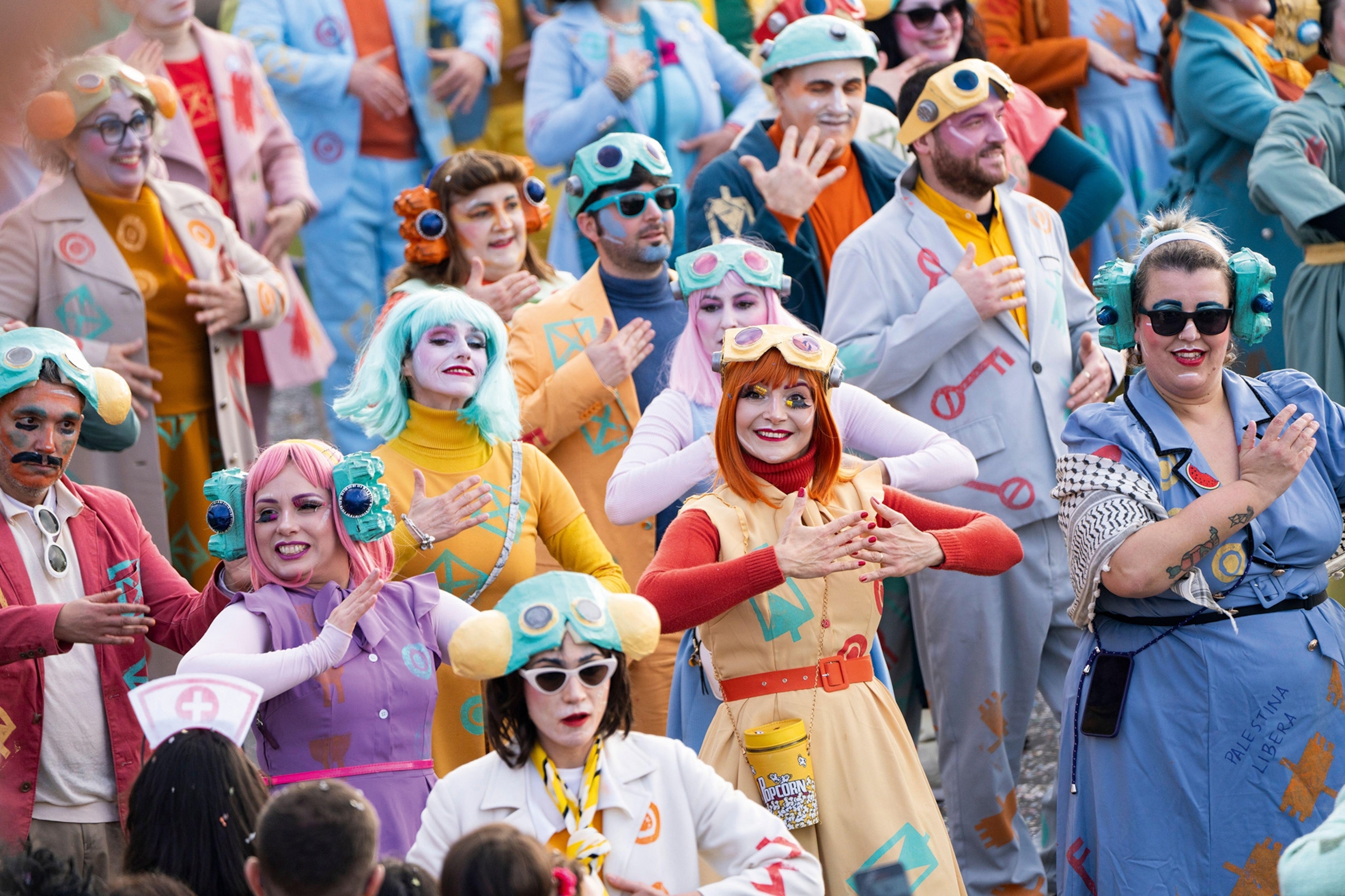 People dressed in colourful costumes and face paint dance in a parade