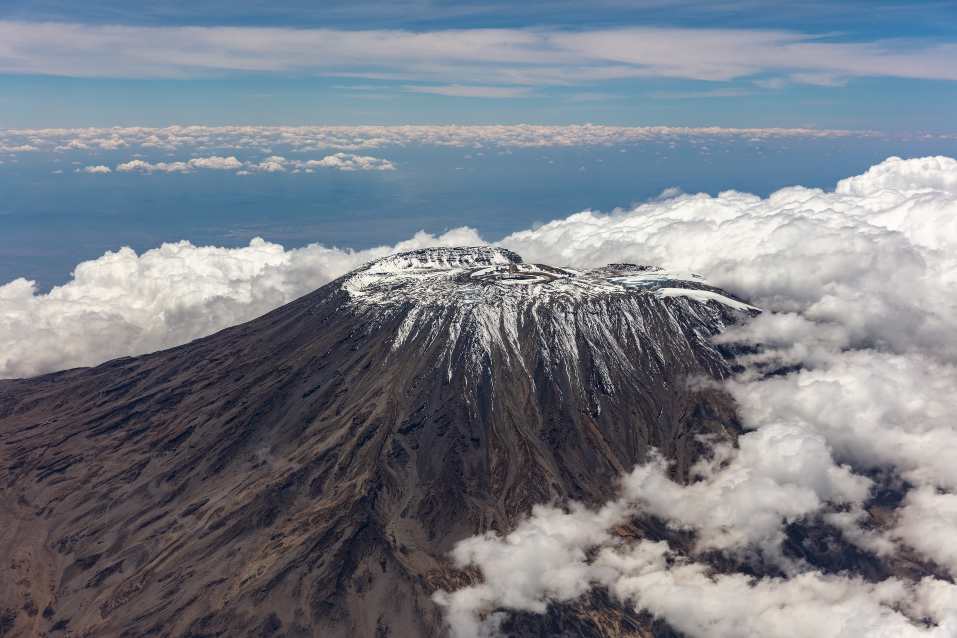 Clouds surround the summit of Kilimanjaro with a light dusting of snow, seen from the air.