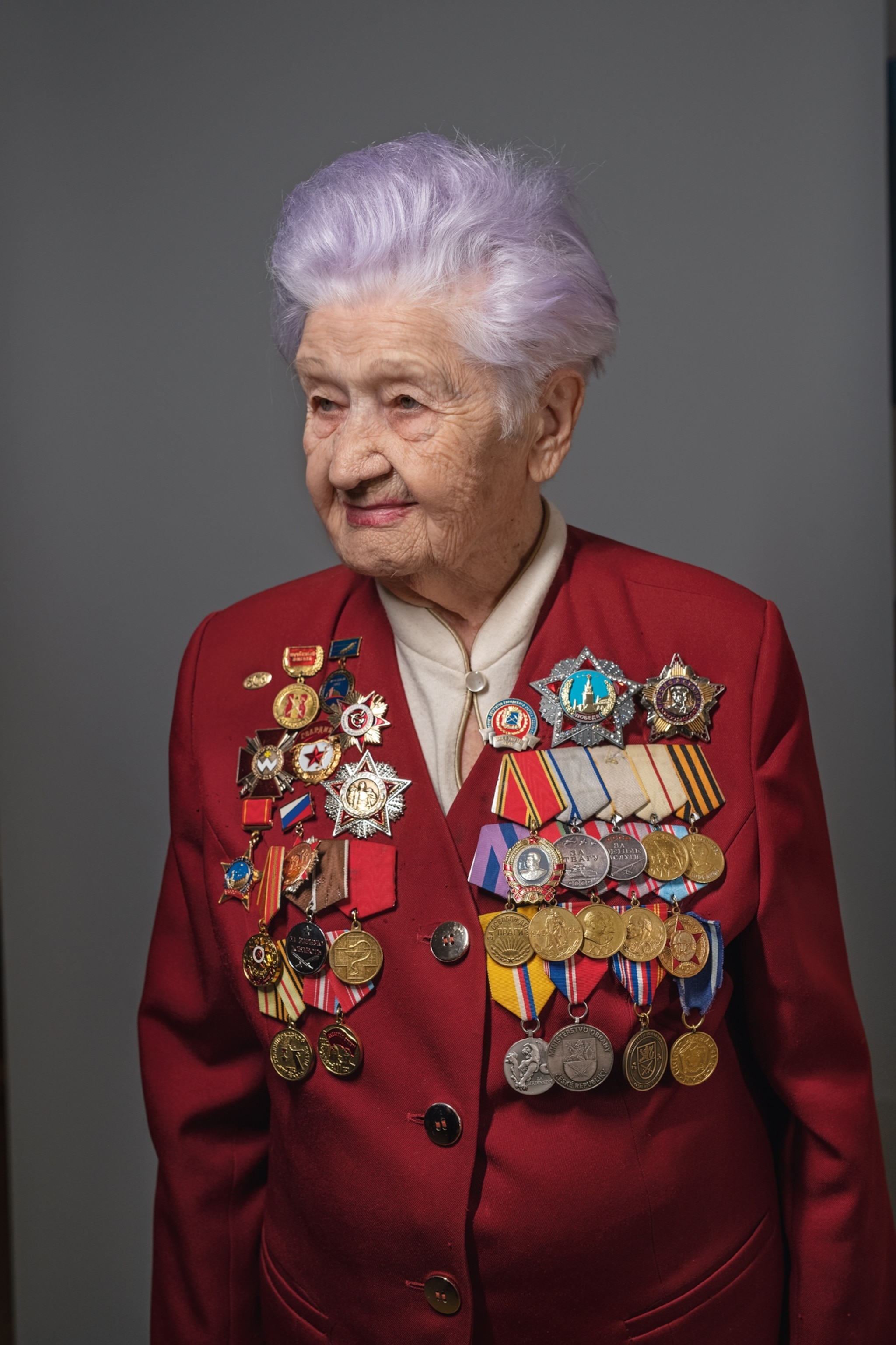 an older woman with purple hair wearing a lot of war medals
