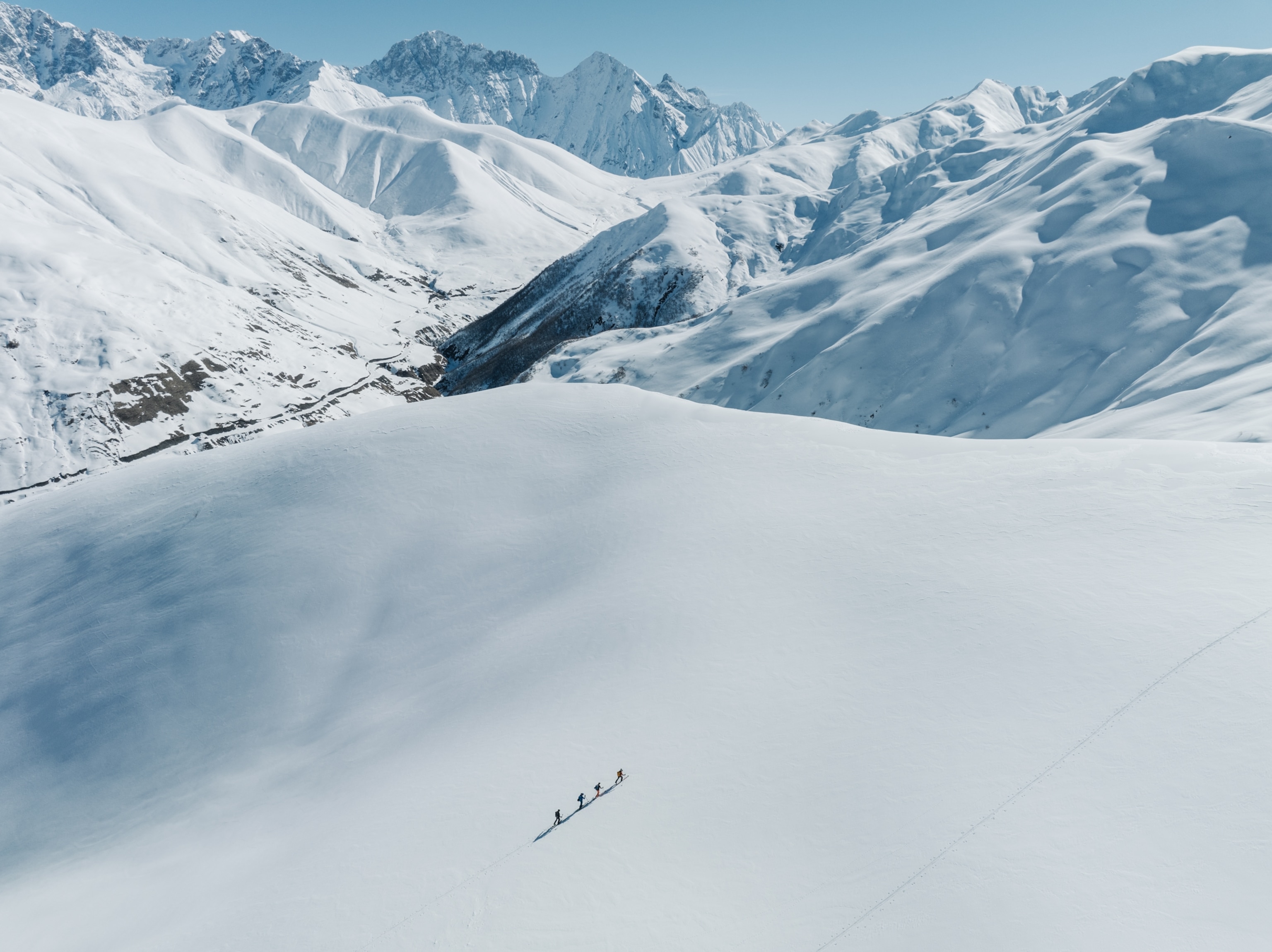 A line of tourists Ski touring at Gvibari pass in Svaneti with the mountains in the background