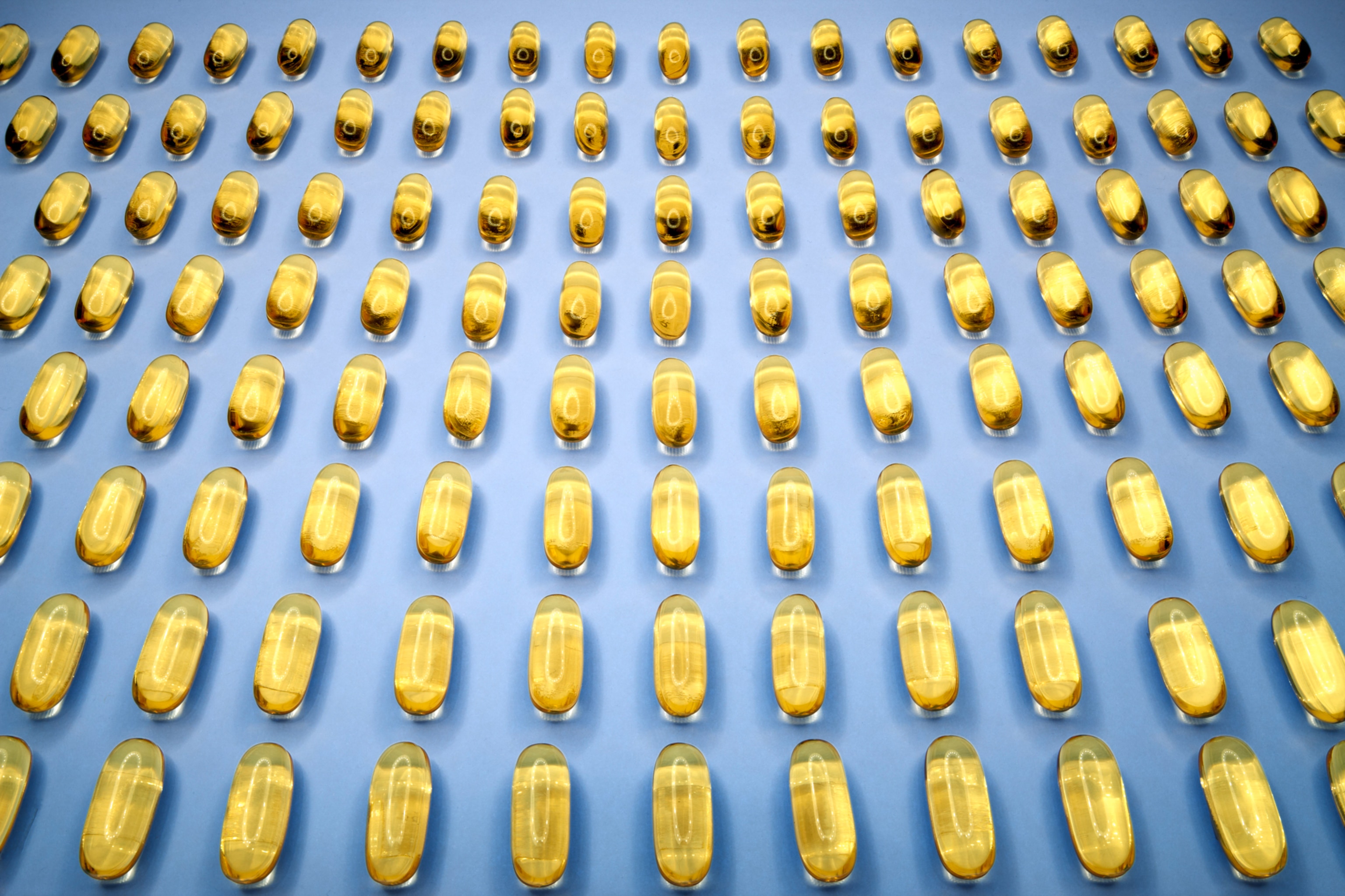 Rows of gel capsules on a blue surface.