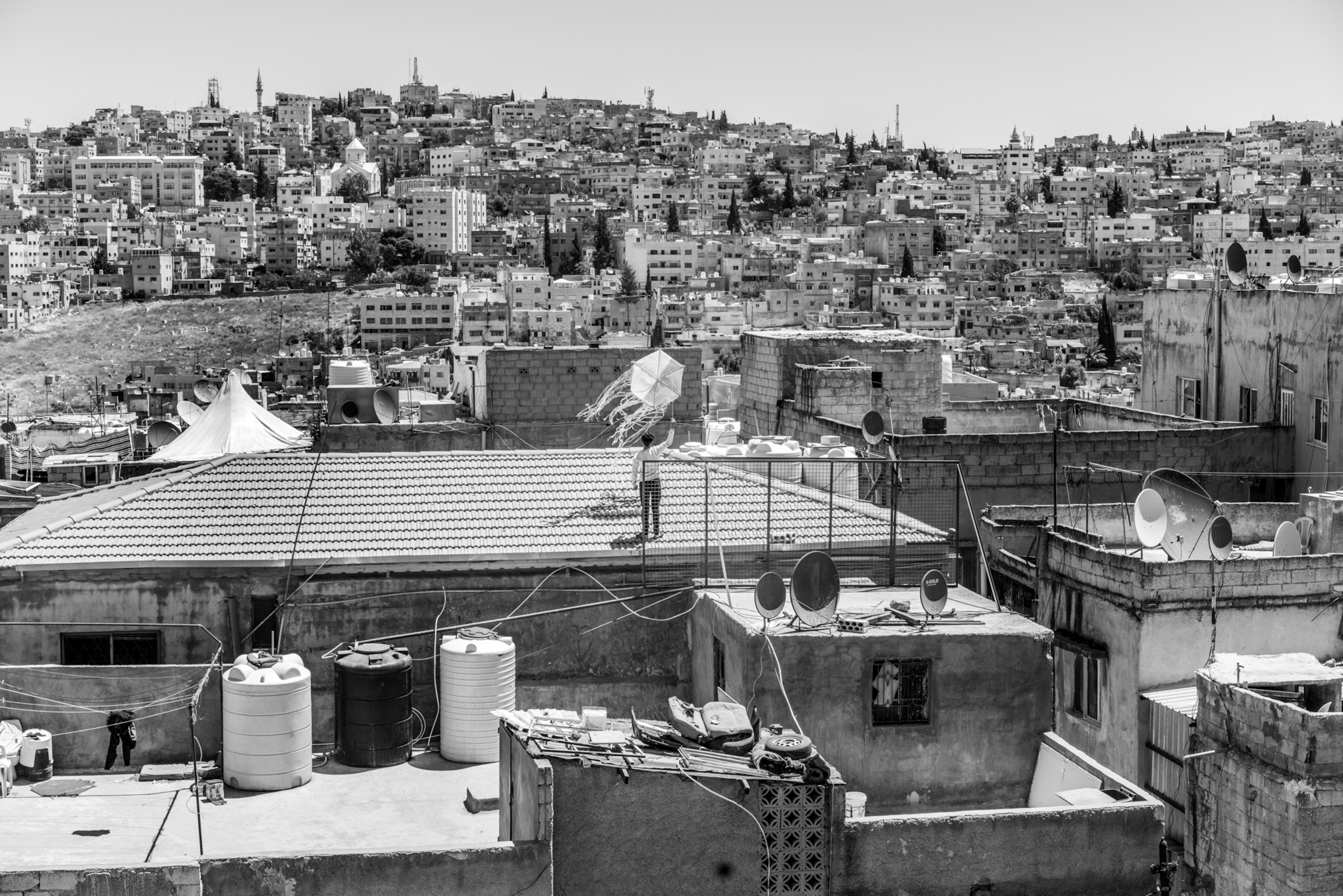 a boy flies a kite on his rooftop in Amman, Jordan