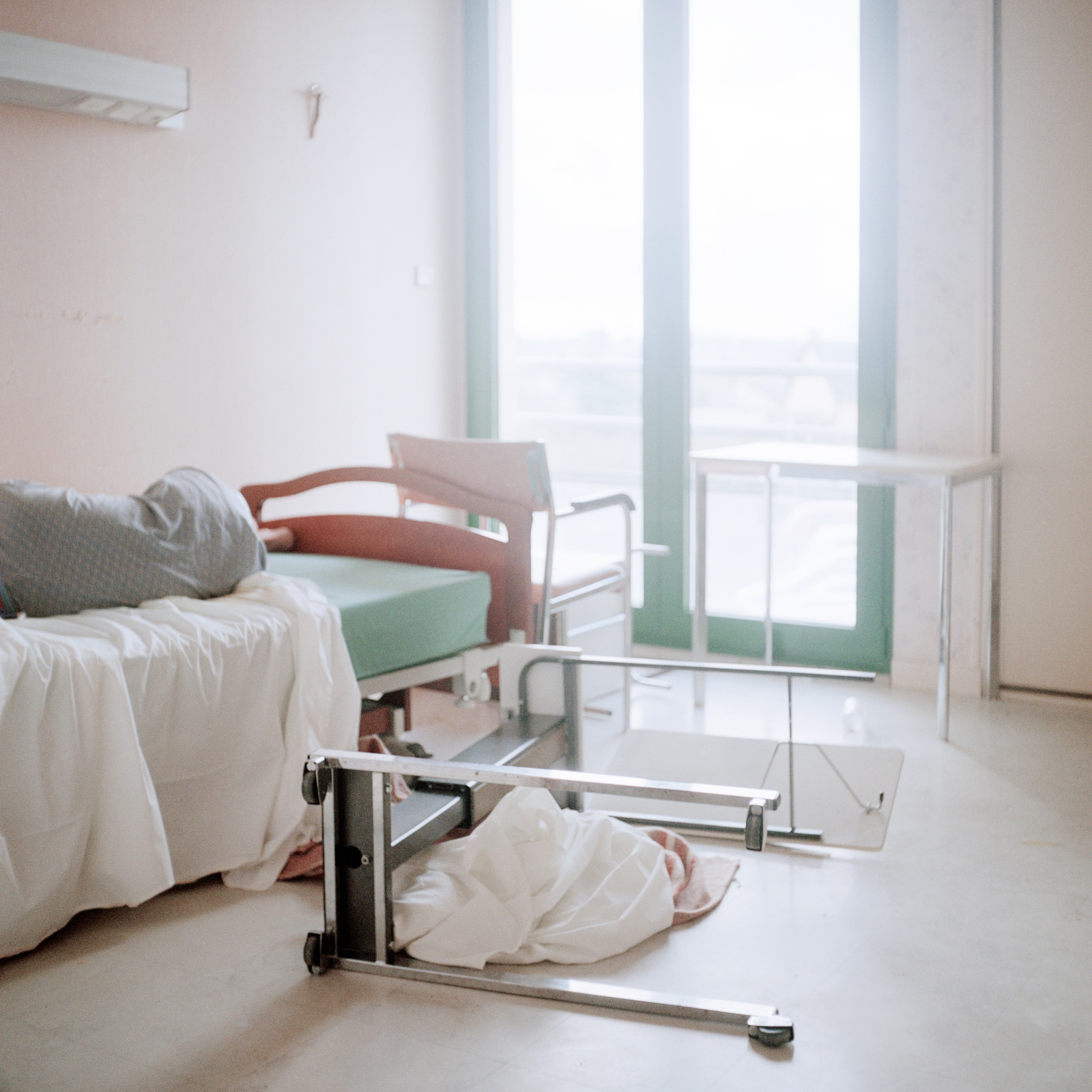 A bedside table and its contents lie strewn across the floor of a resident's room.