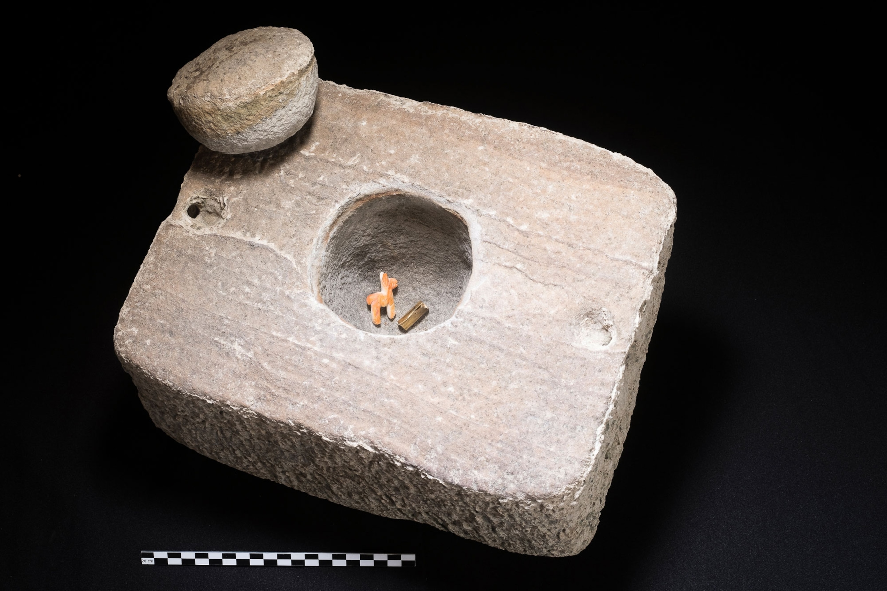 a stone square box with a small round top with artifacts inside
