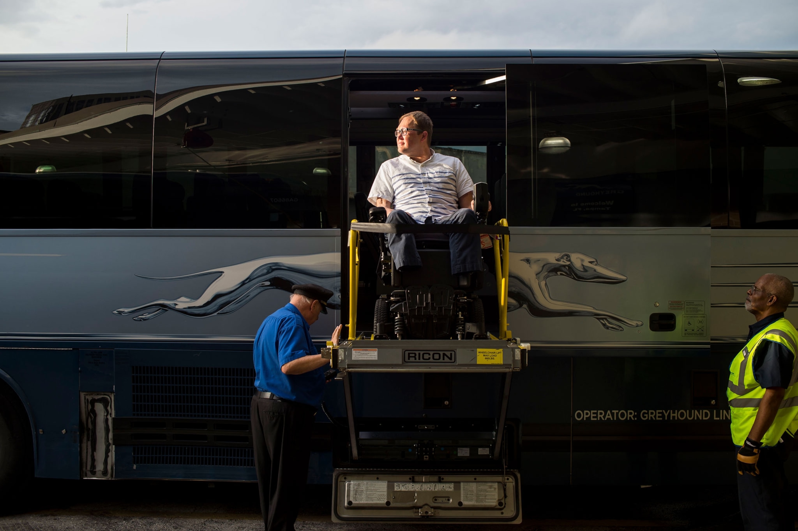 A photograph of a man using a wheelchair lift on a bus