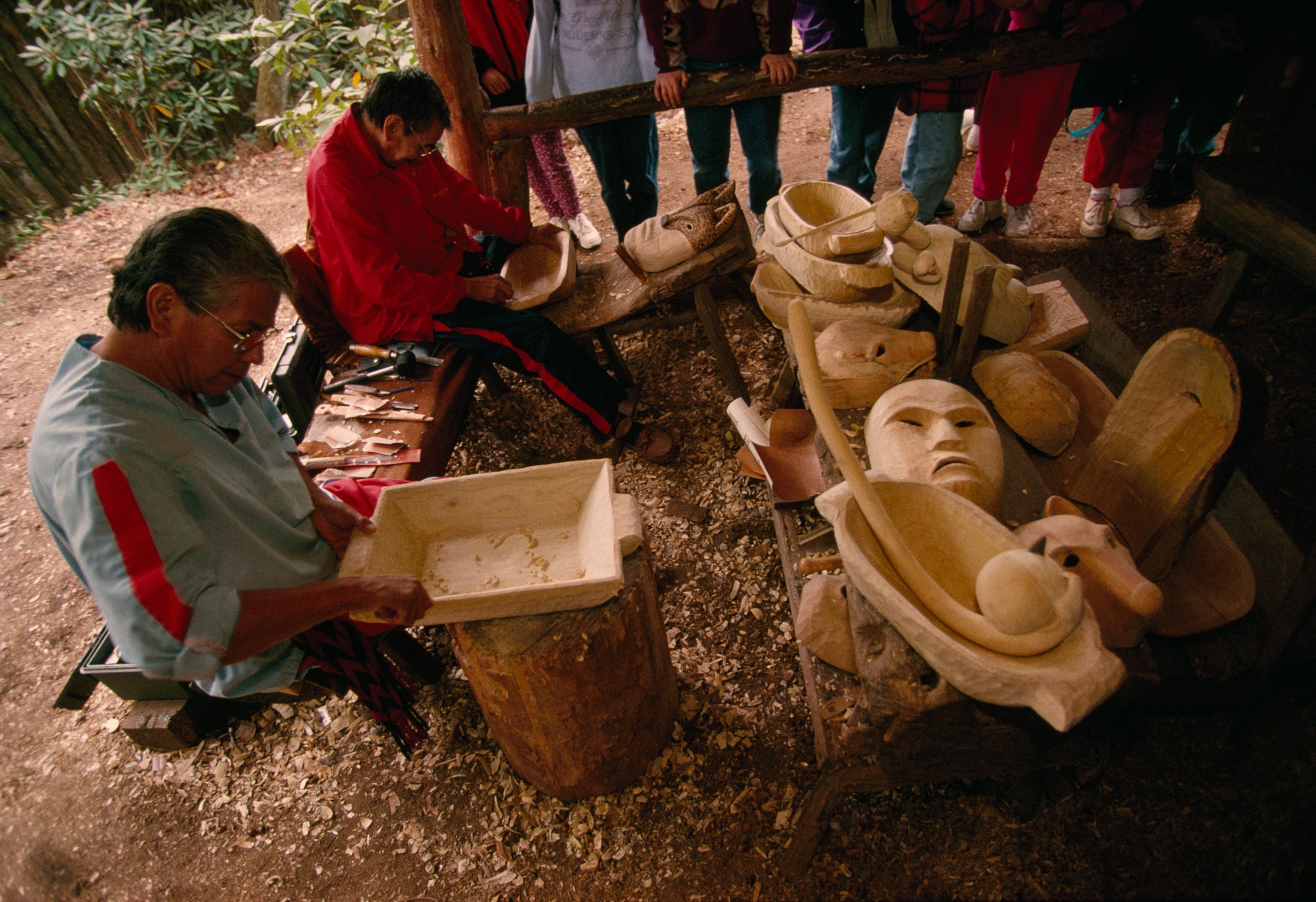 People sit down carving wood.
