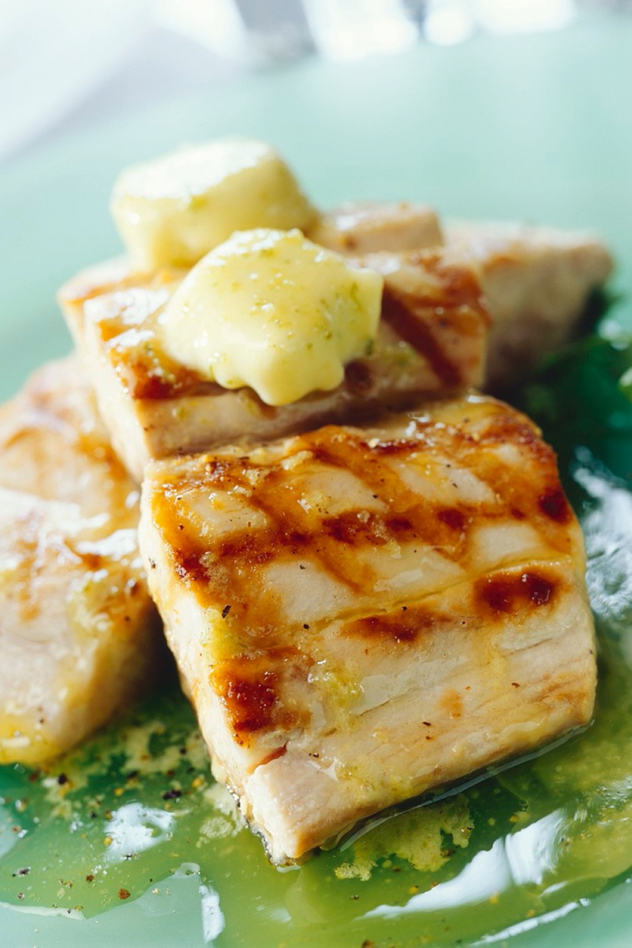 A plated and grilled fish fillet topped with a knob of butter.