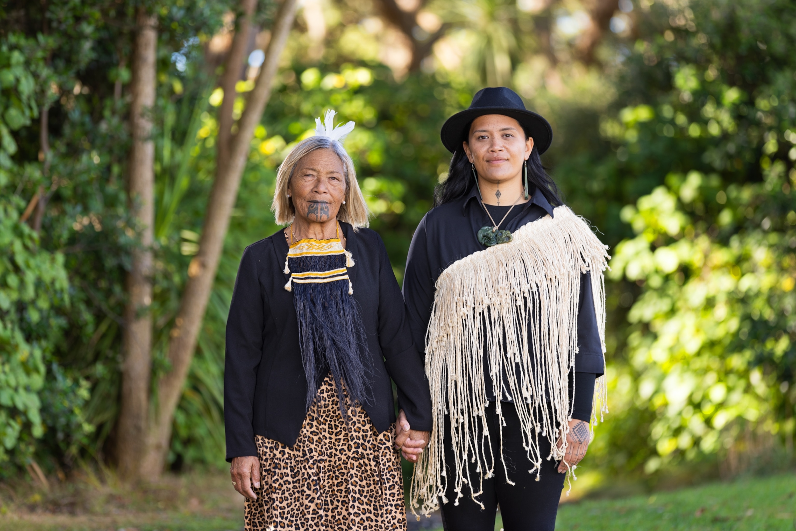 Young and older women in traditional clothes holding hand before the camera.