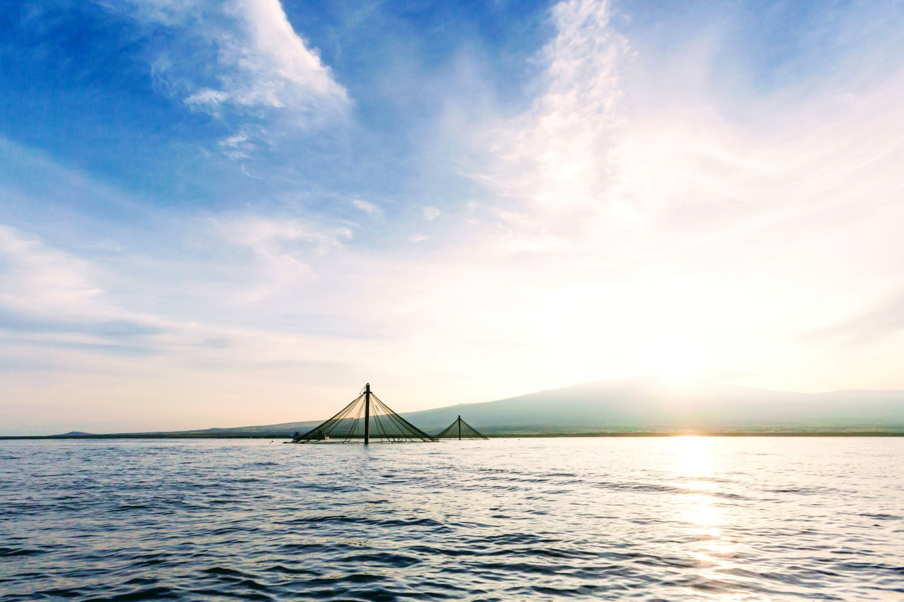 Two fish pens partially submerged in the ocean.