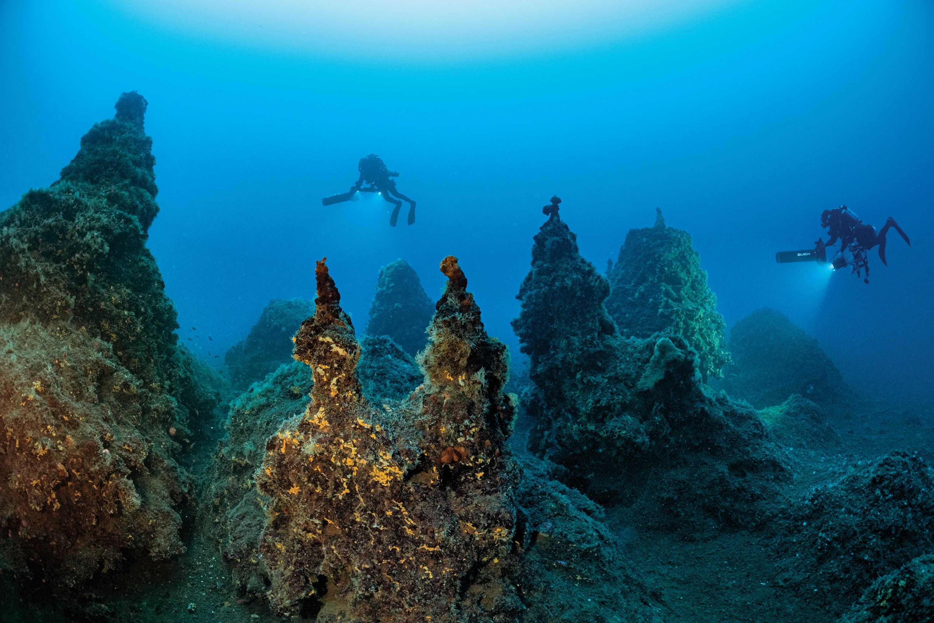 Two divers over volcanic cones.