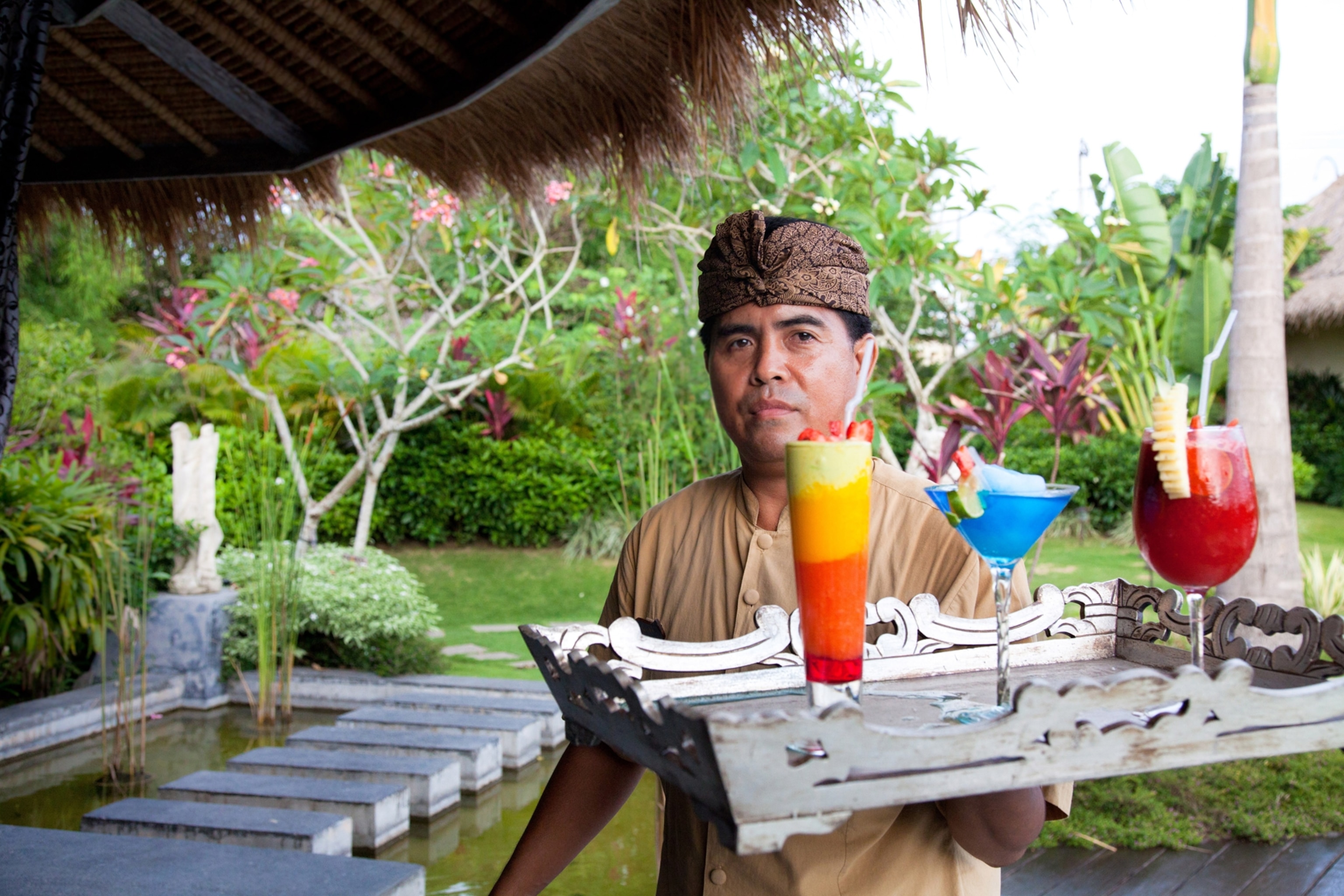a waiter balances drinks at a resort in Bali