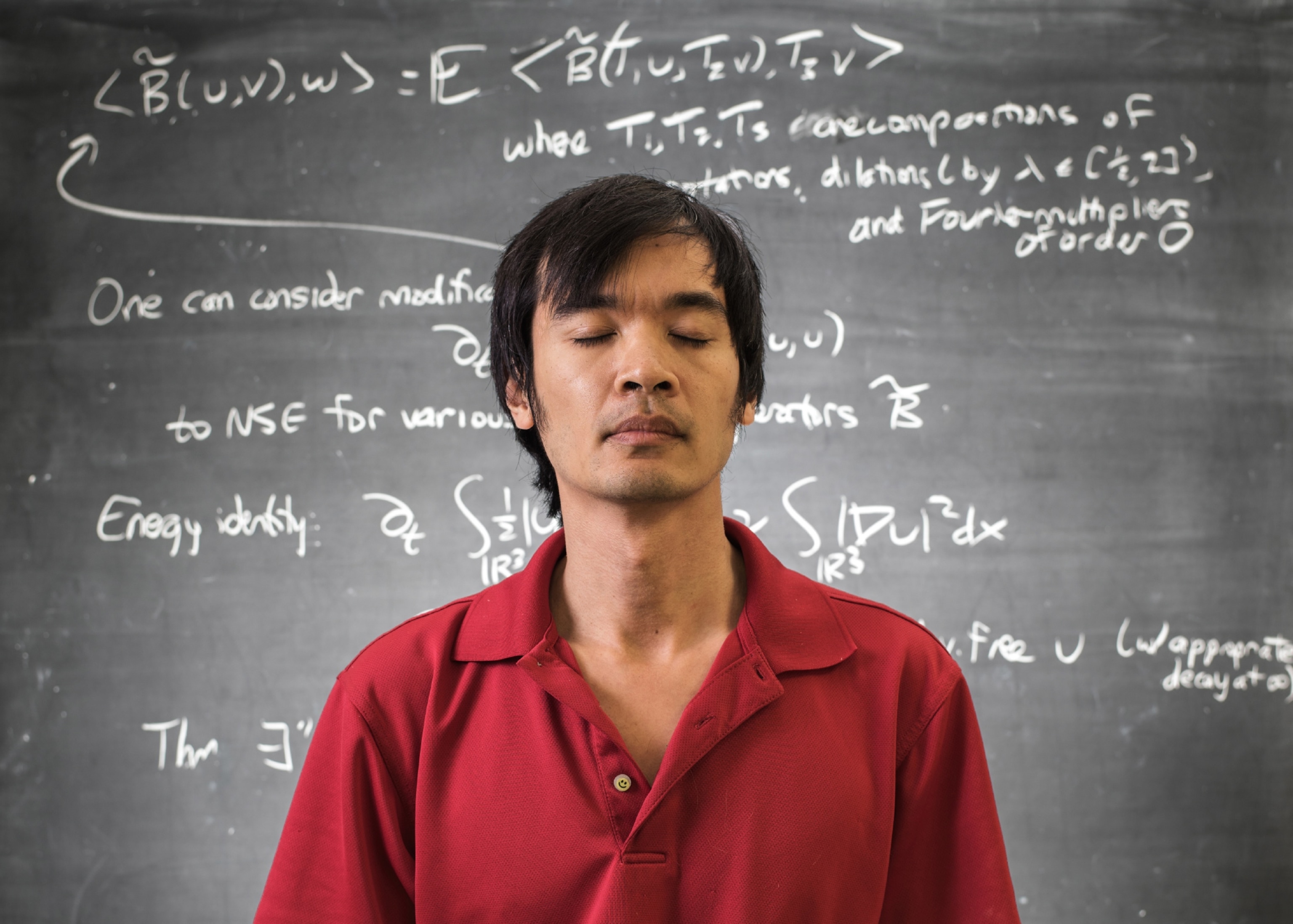 mathematician with his formulas written on the blackboard behind him.