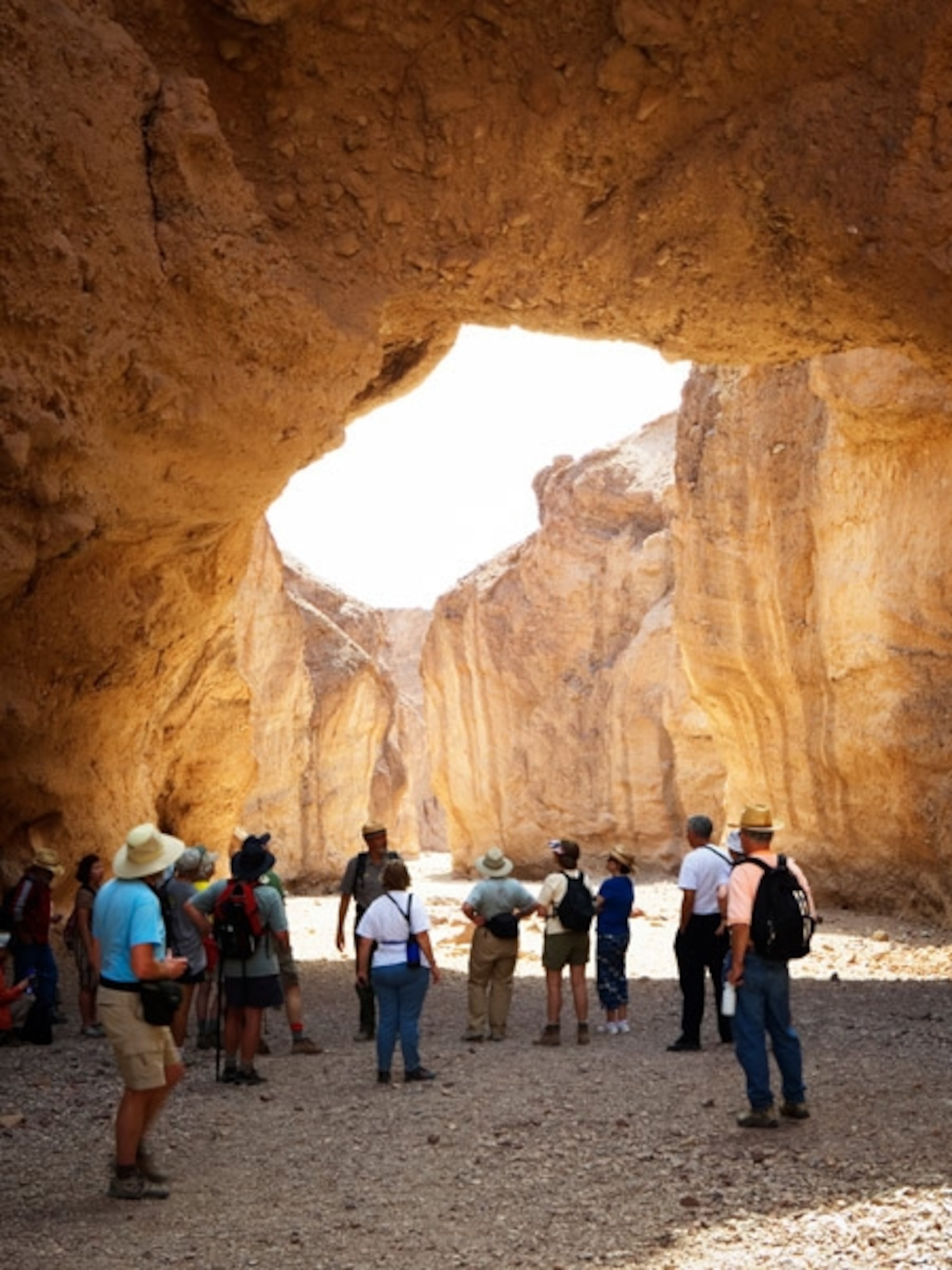 People under an arch in a desert canyon