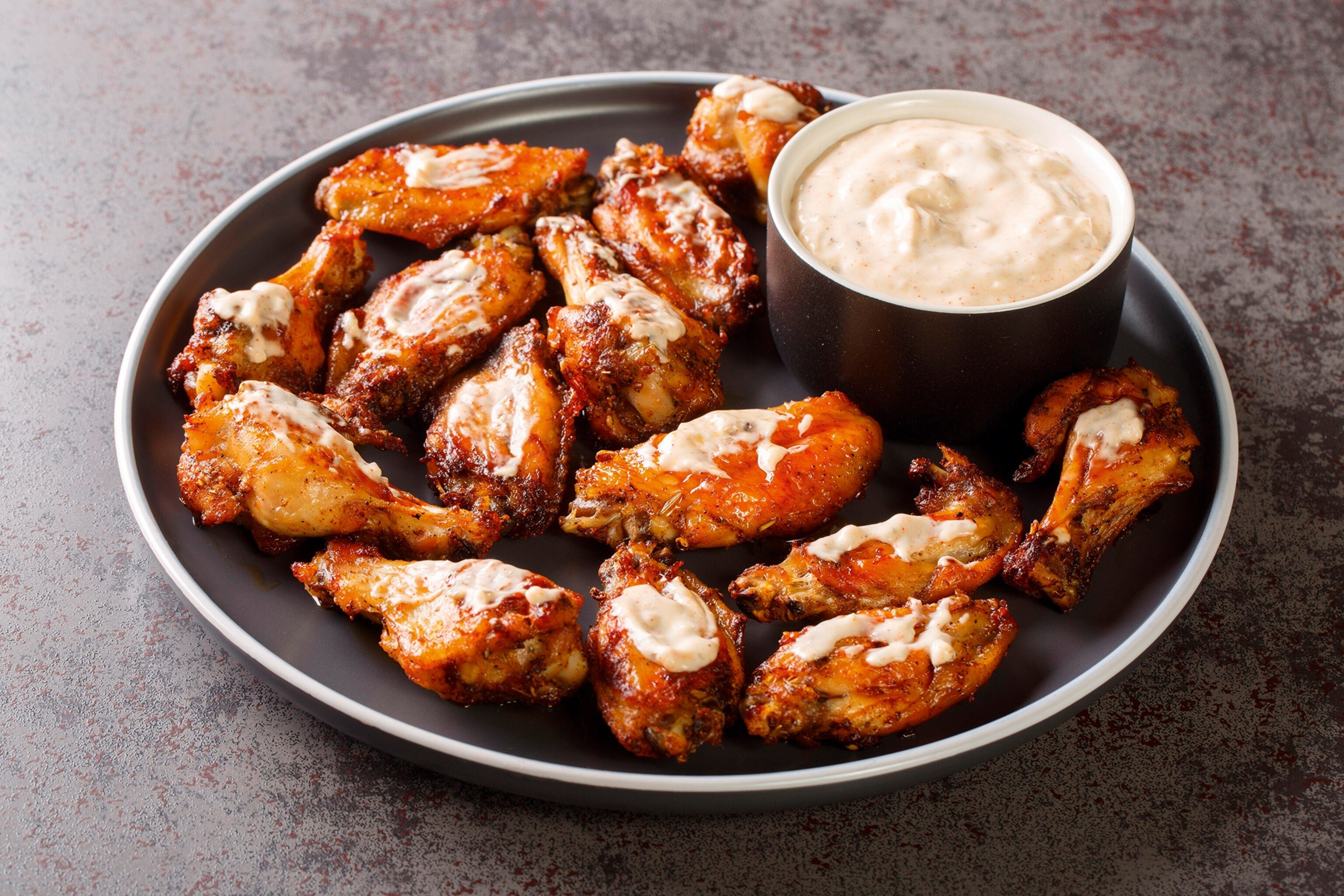 A plate of grilled chicken wings with Alabama white sauce.