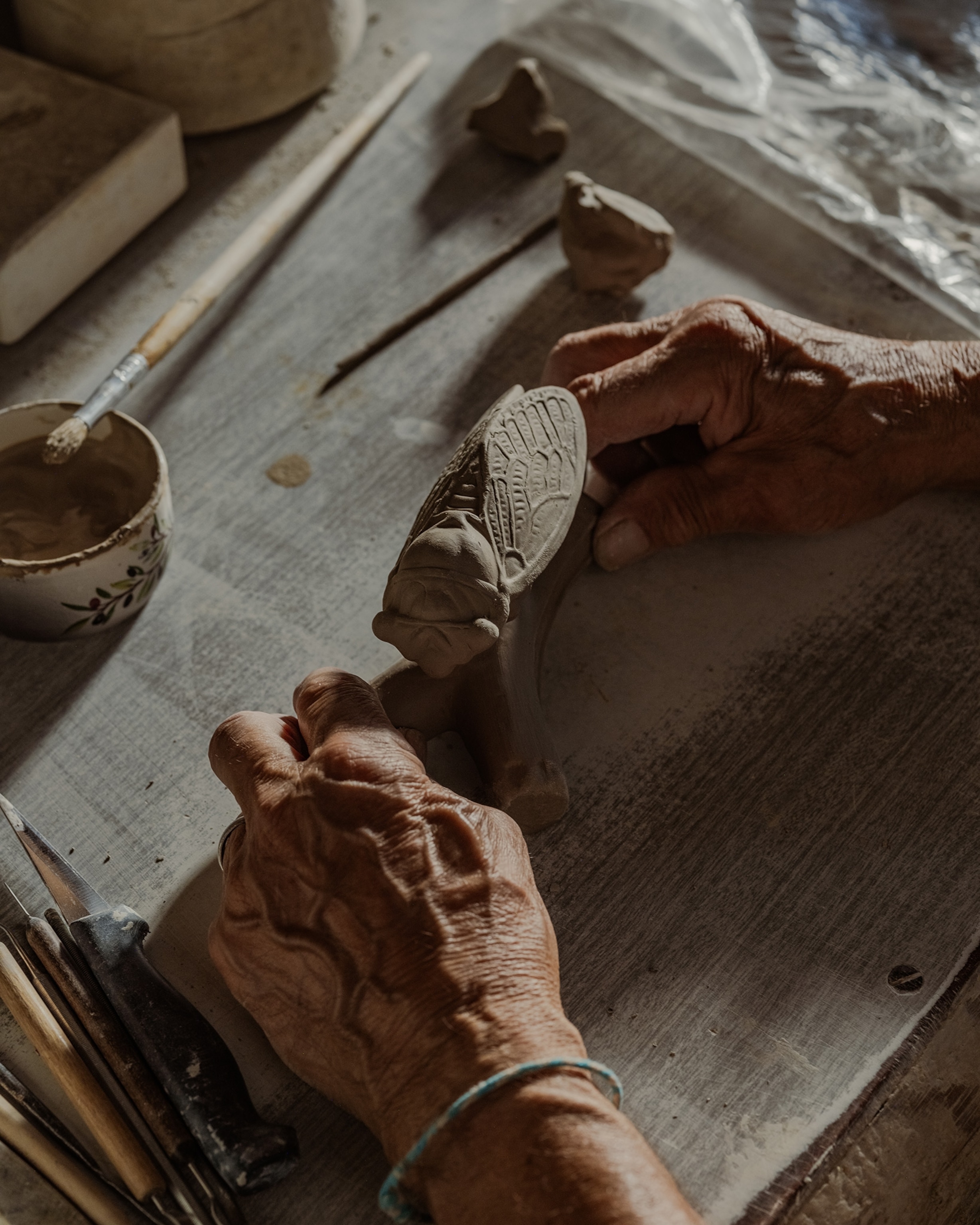 Bernard Amy wets clay to combine the cicada part, the base, and a few additional details like a leaf.