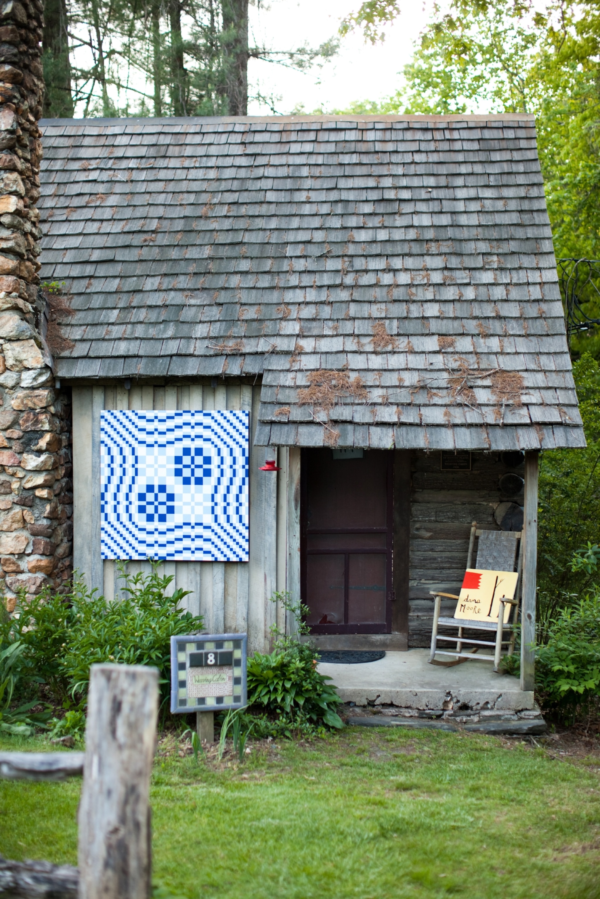 Small old cabin in the woods with artwork hanging on the exterior