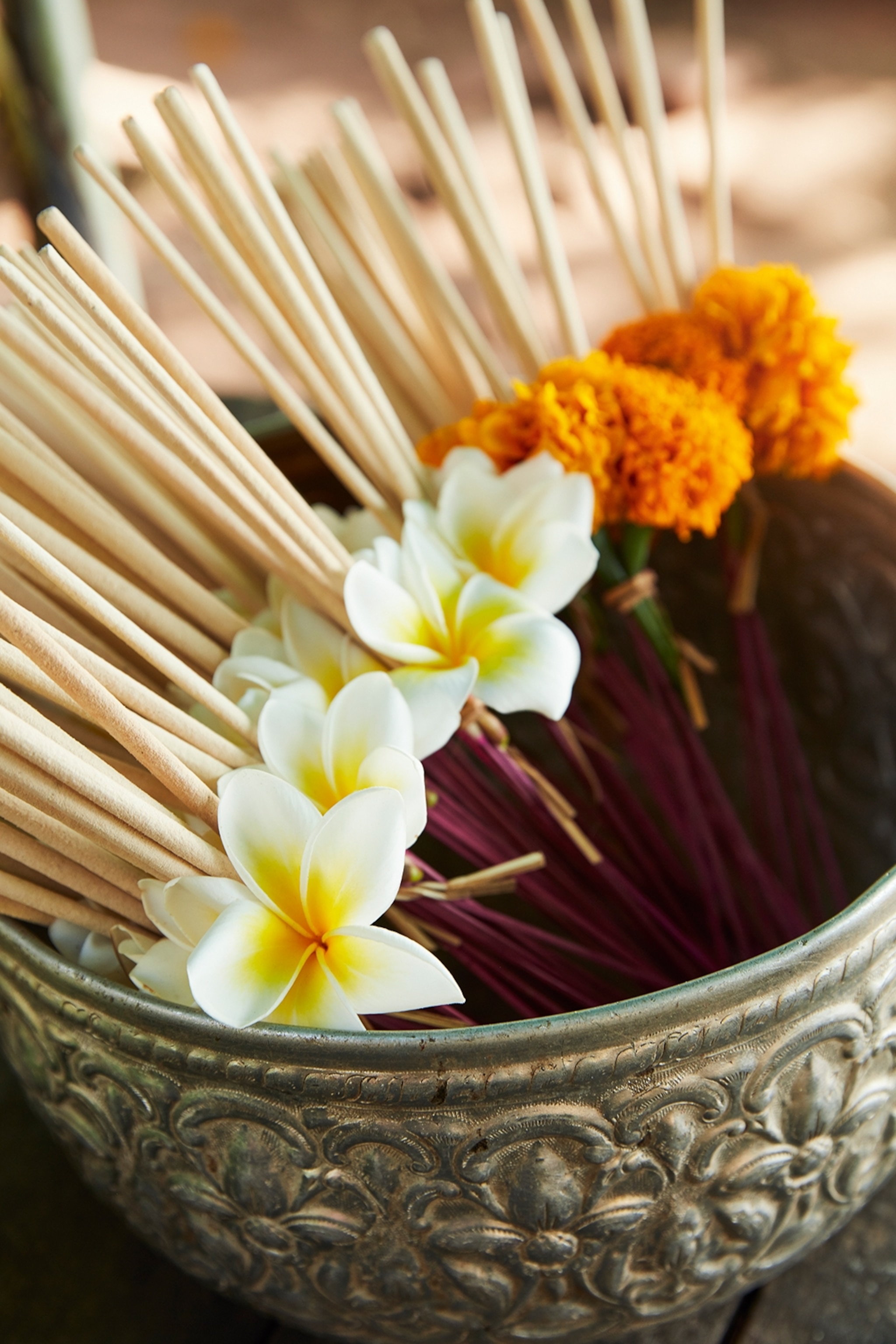A bowl of frangipani flower offerings, with flowers tied to small sticks.