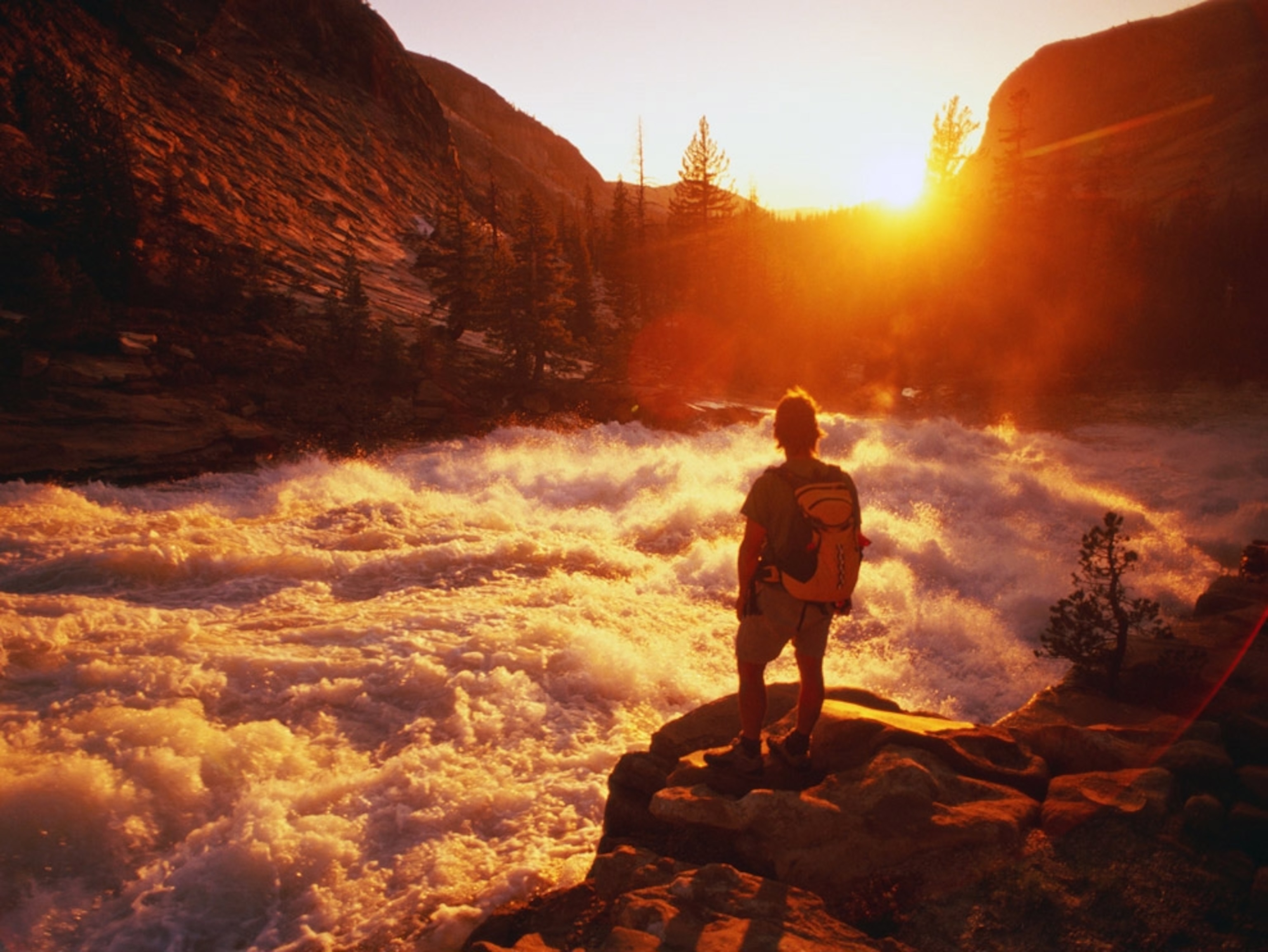 Hiker overlooks white water rushing between canyons