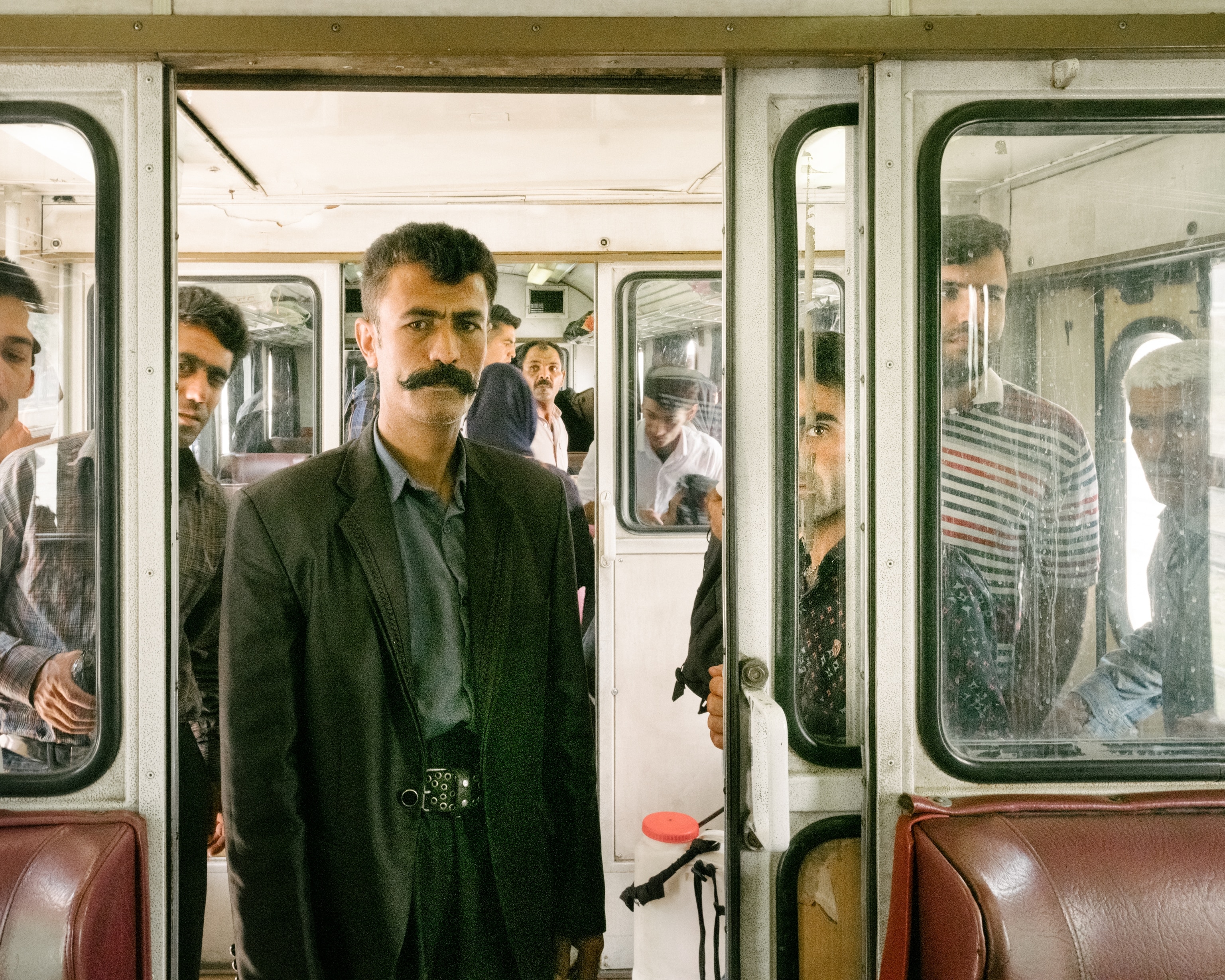 People stand among the seats in a train car