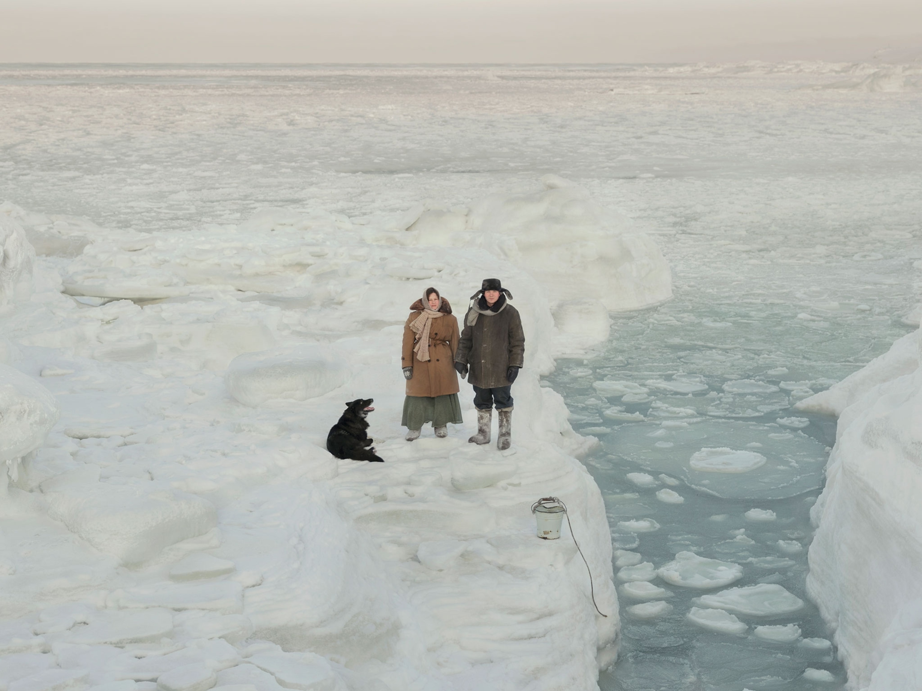 man and women bundled in winter coats with a dog.