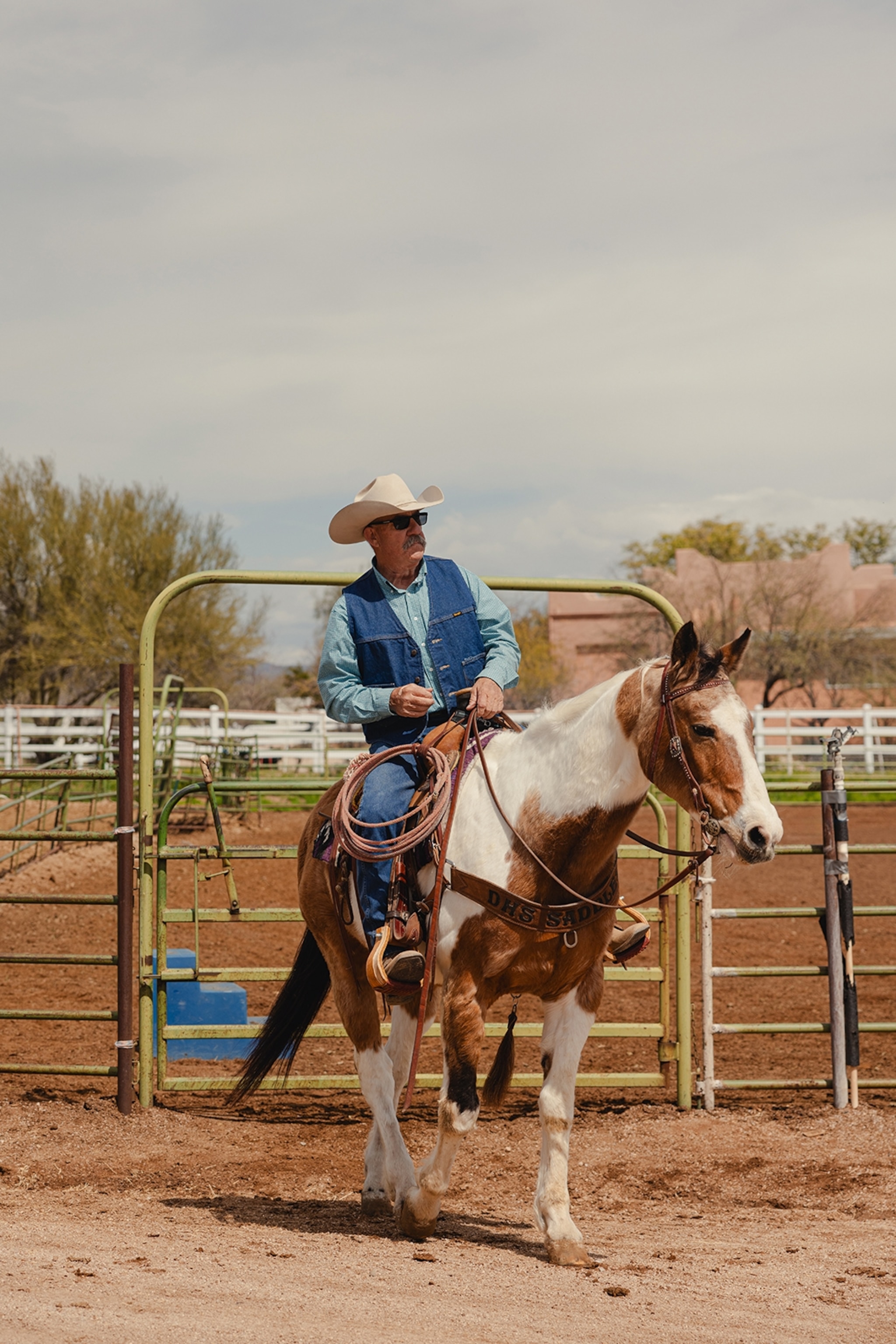 A man riding a horse in Arizona. He is wearing a blue shirt and a blue denim waist coat