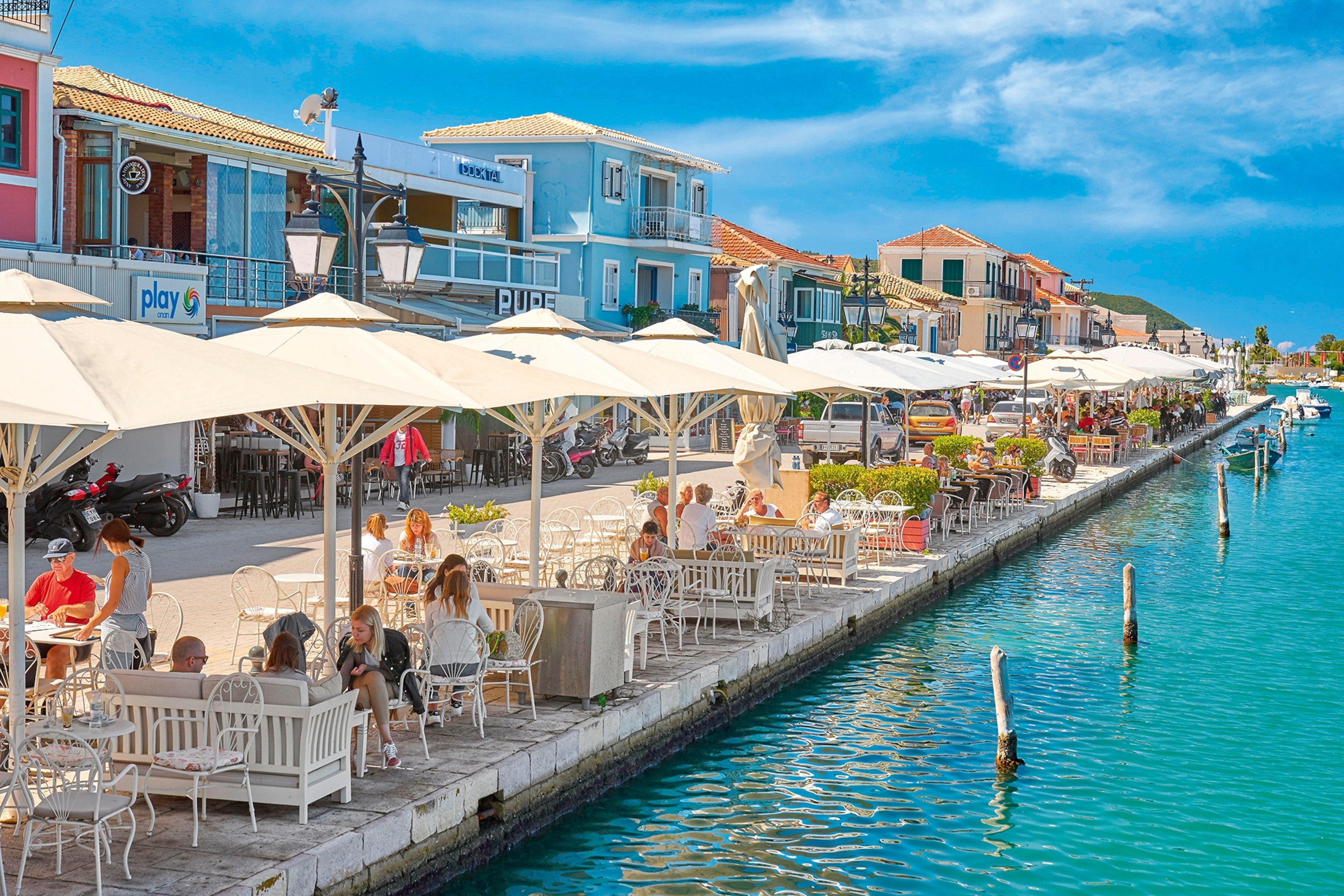 A waterfront promenade with restaurants and bars overlooking the sea.
