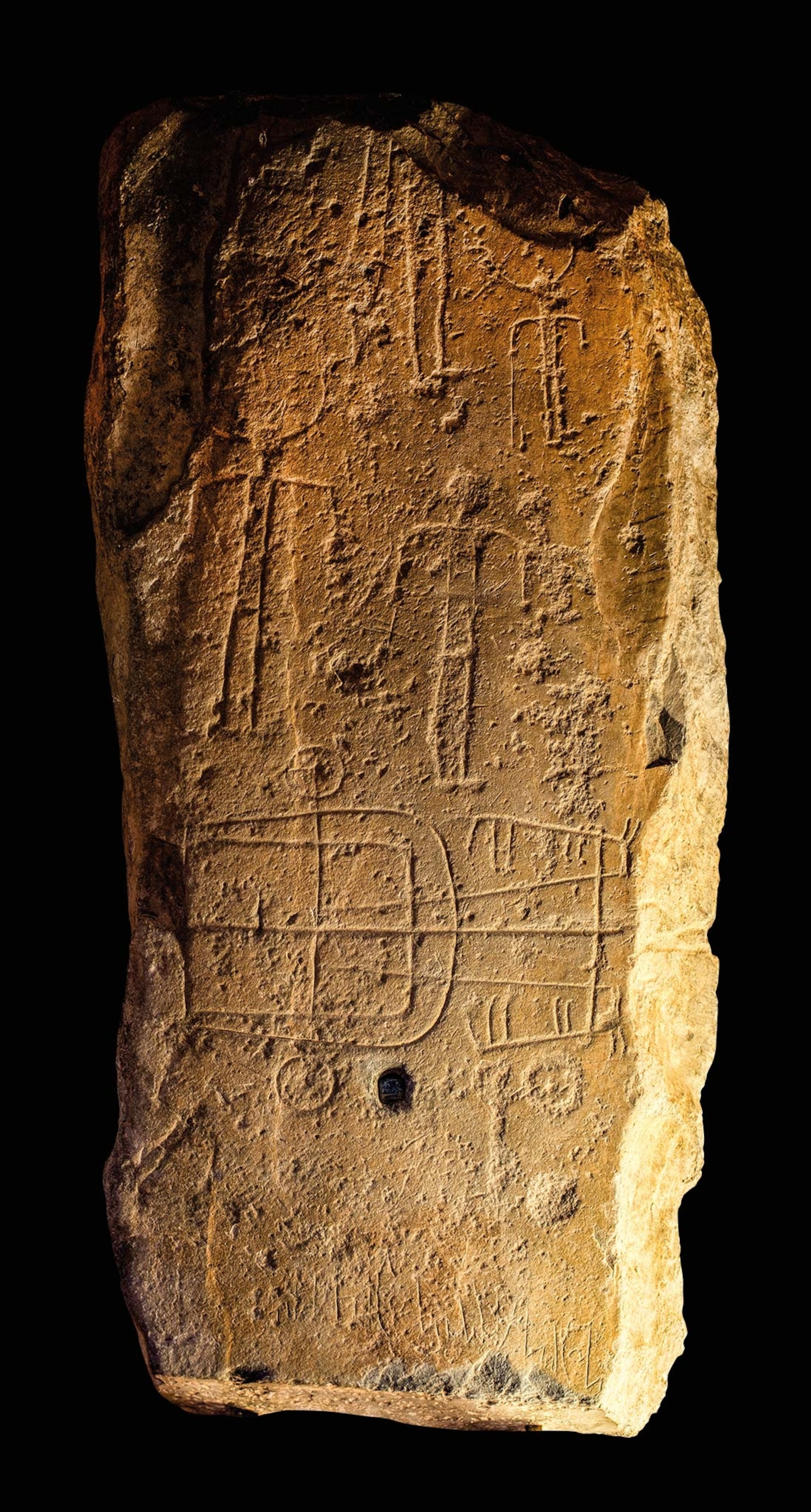 A rock with writing and figures of warriors on it