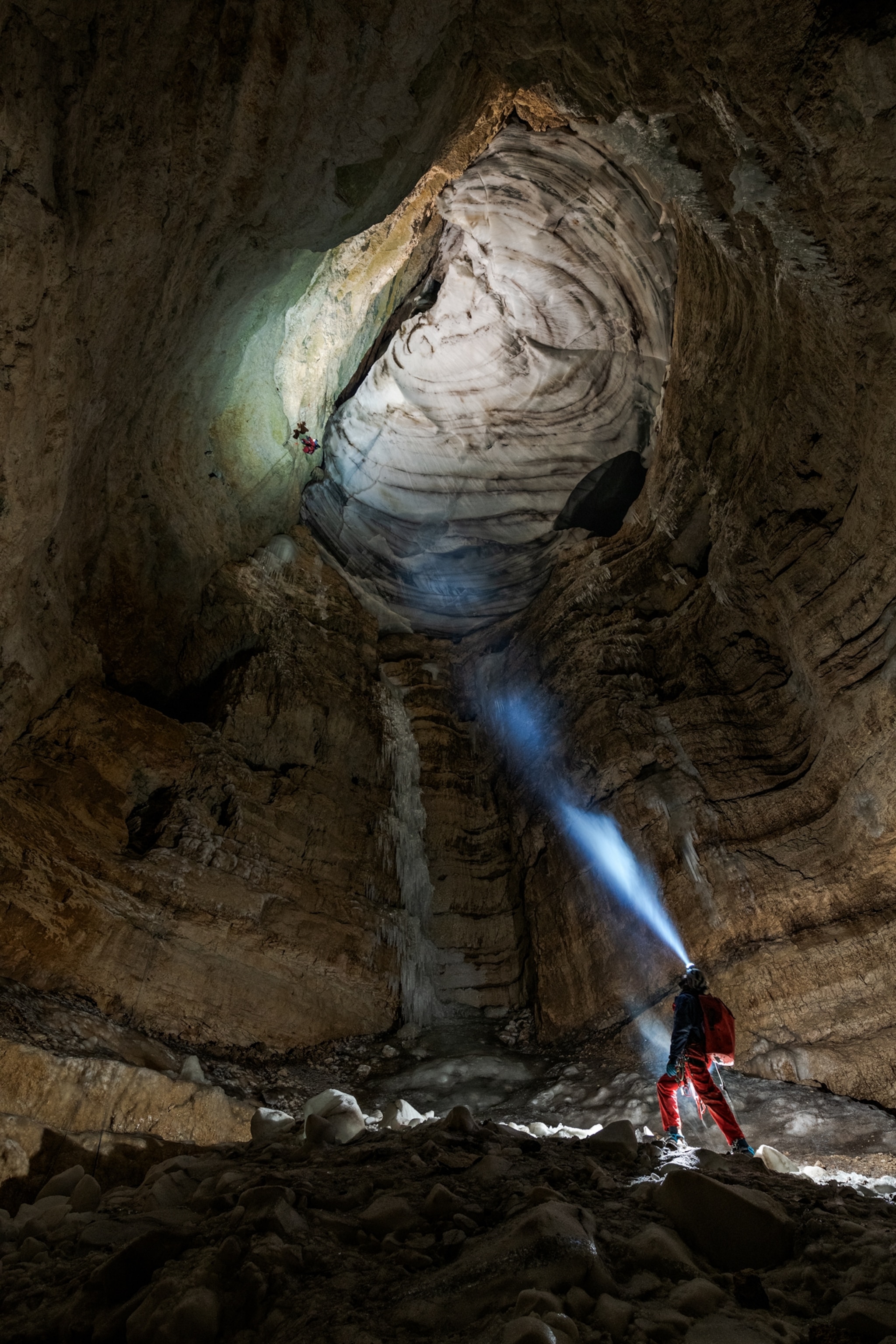 Picture of person looking at another one hanging on a rope high above.